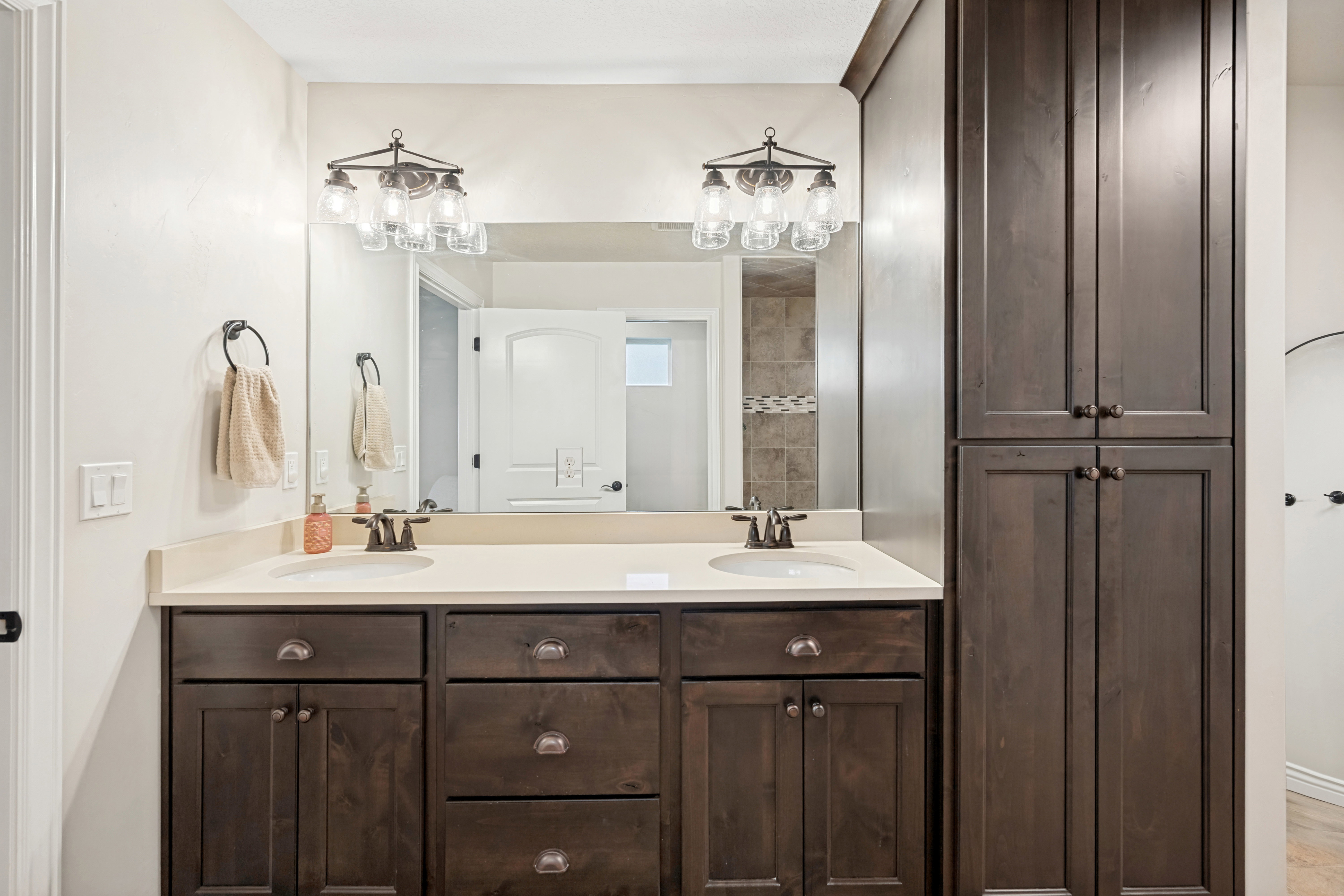 Dual vanity with integrated sinks, light-toned countertop, and dark wood-finish cabinetry