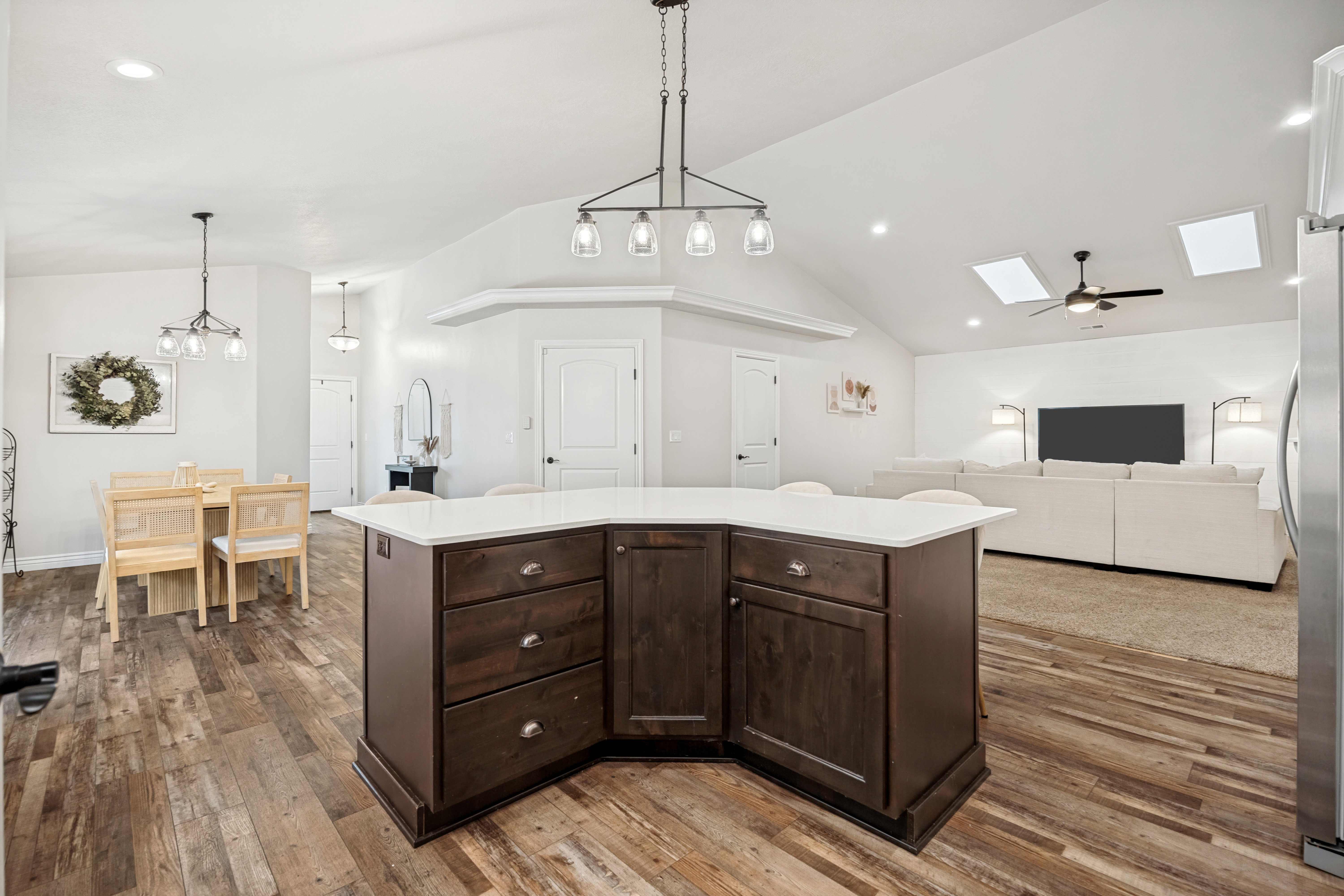 Kitchen island with dark wood cabinetry and a light-toned countertop, positioned on wood-finish flooring