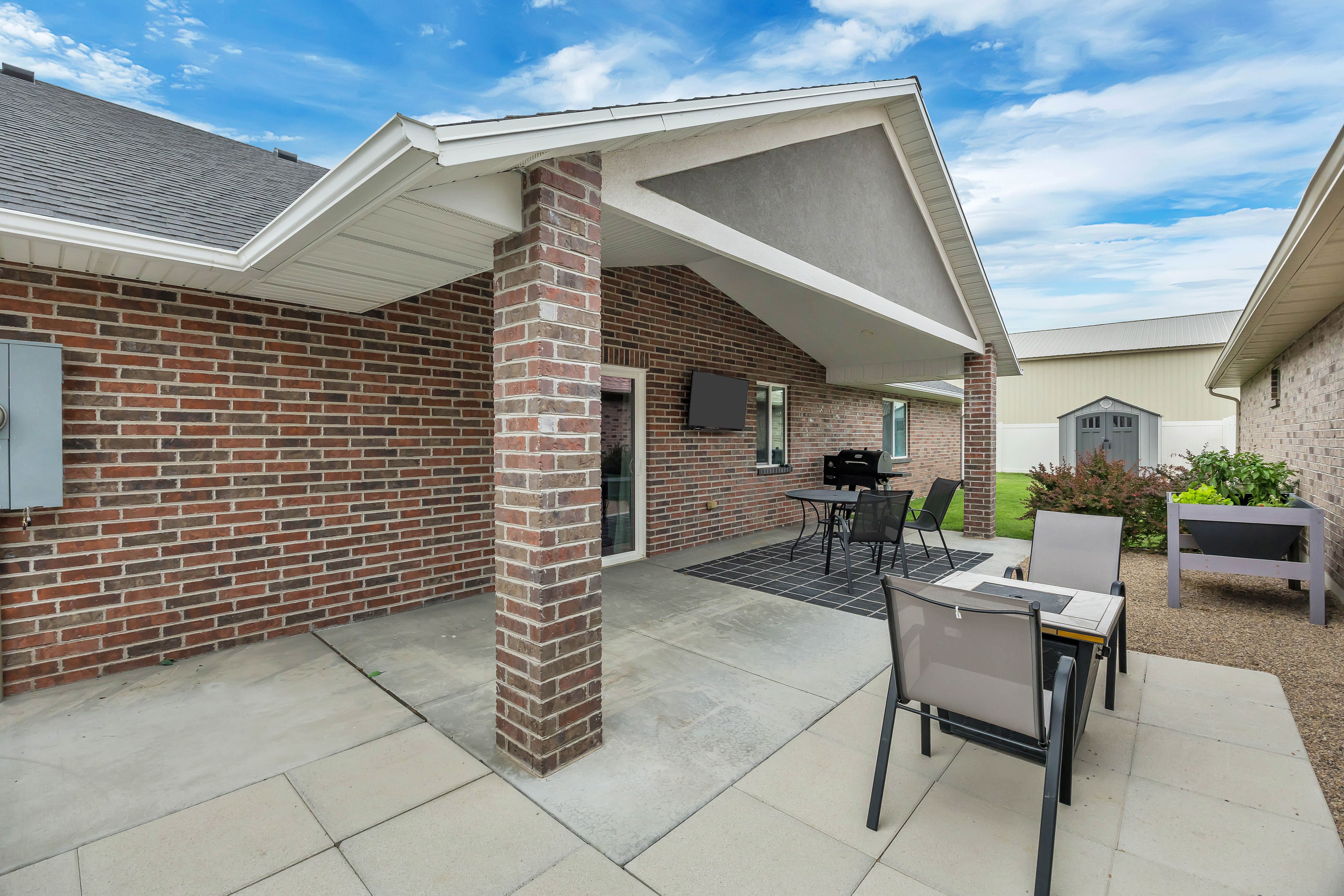 Expansive concrete patio area with a brick column and a covered section
