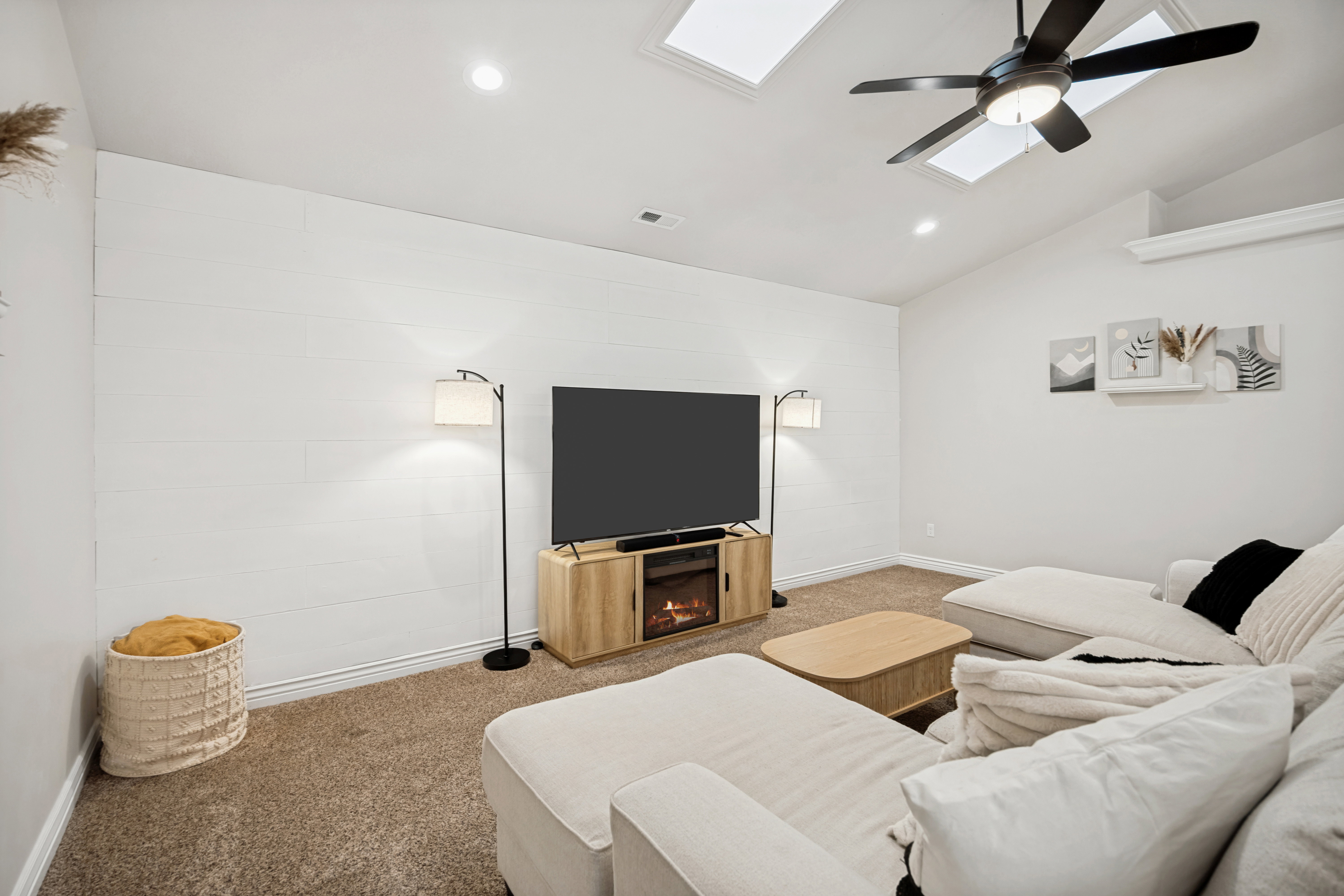 Living area featuring vaulted ceilings, two skylights, recessed lighting, and a ceiling fan