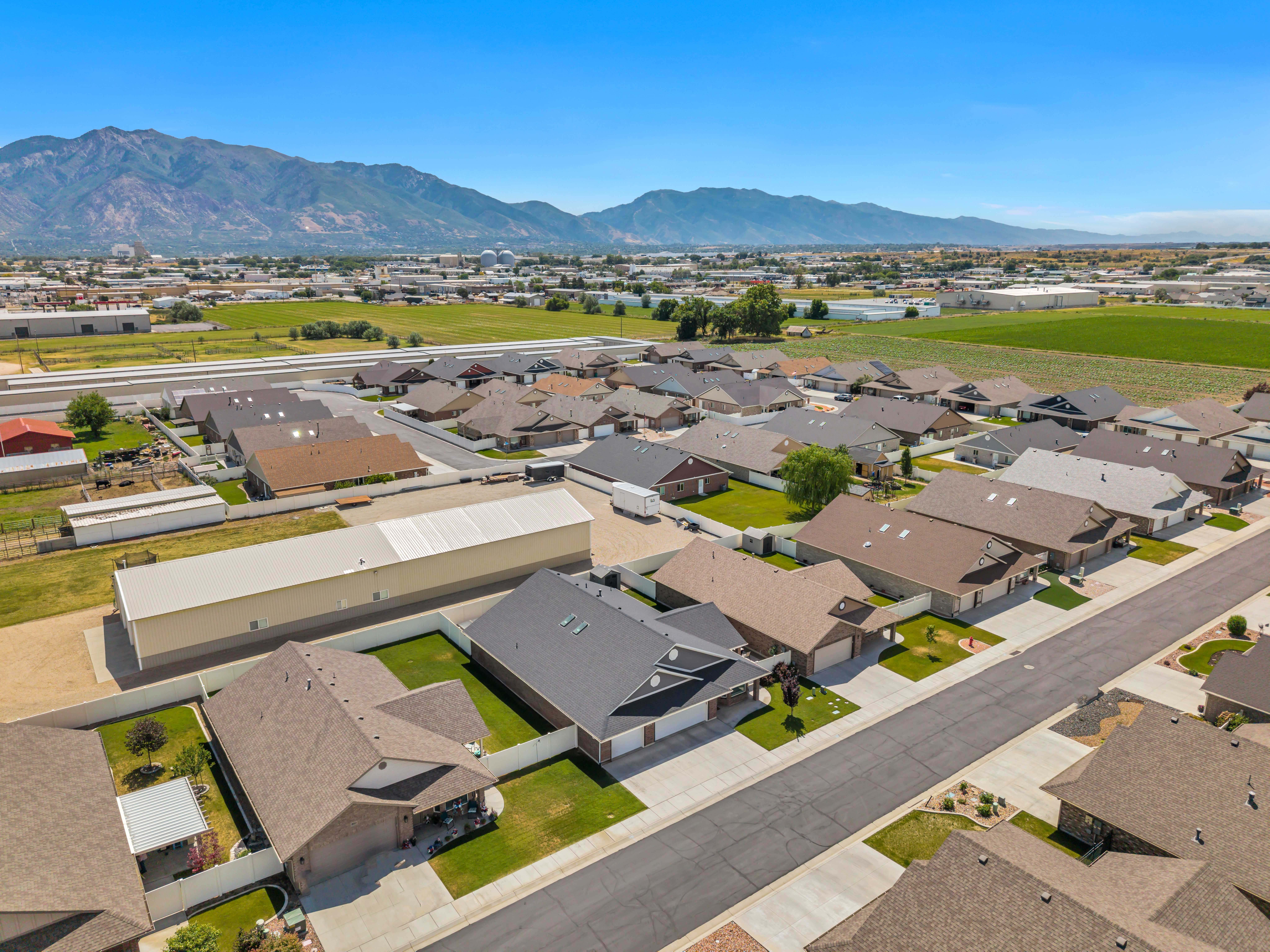 Aerial neighborhood perspective featuring a residential street, uniform rooflines, and mountain scenery