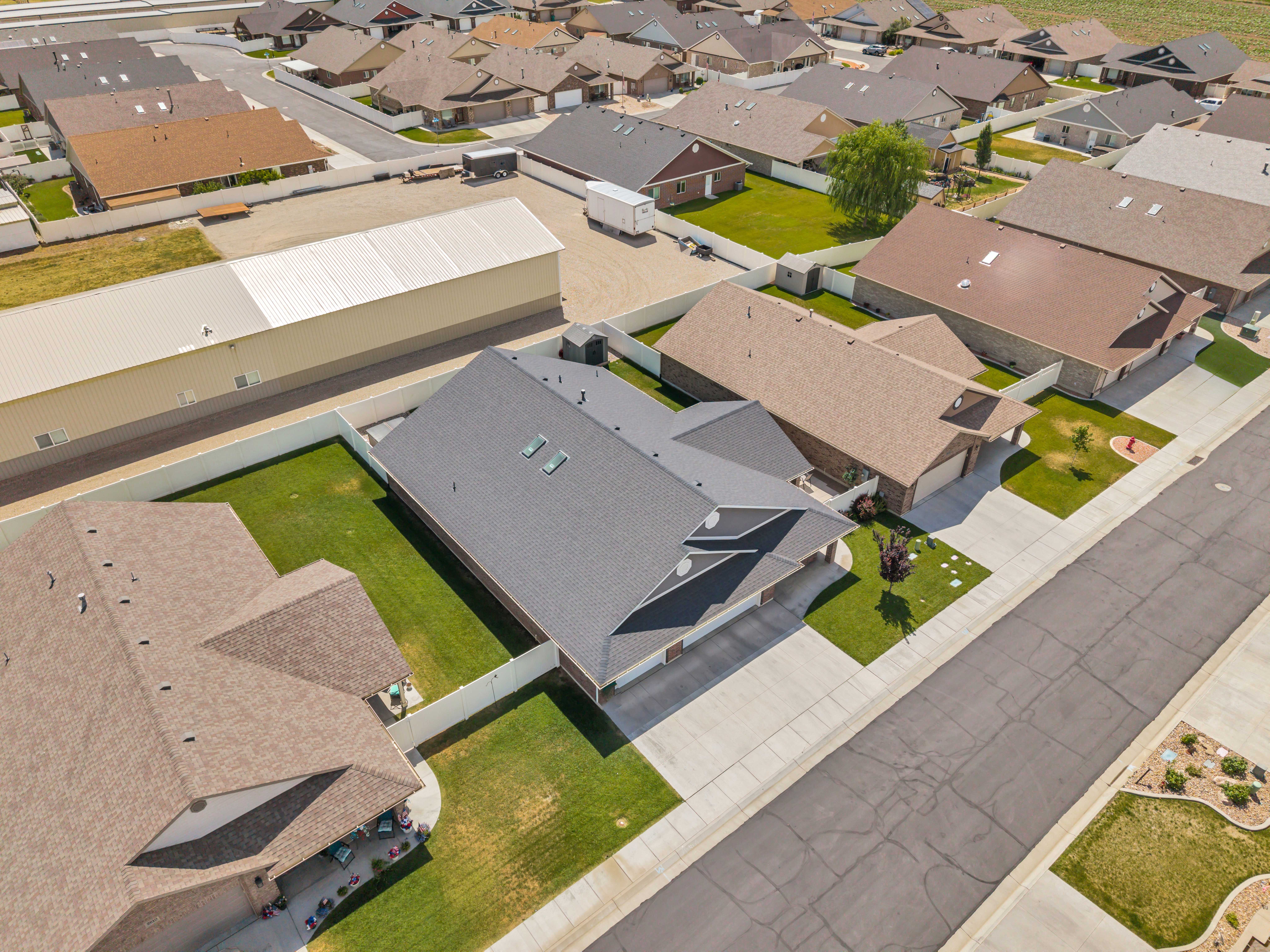 Newly constructed residence featuring a gray asphalt shingle roof with skylights, an attached two-car garage, and a manicured lawn