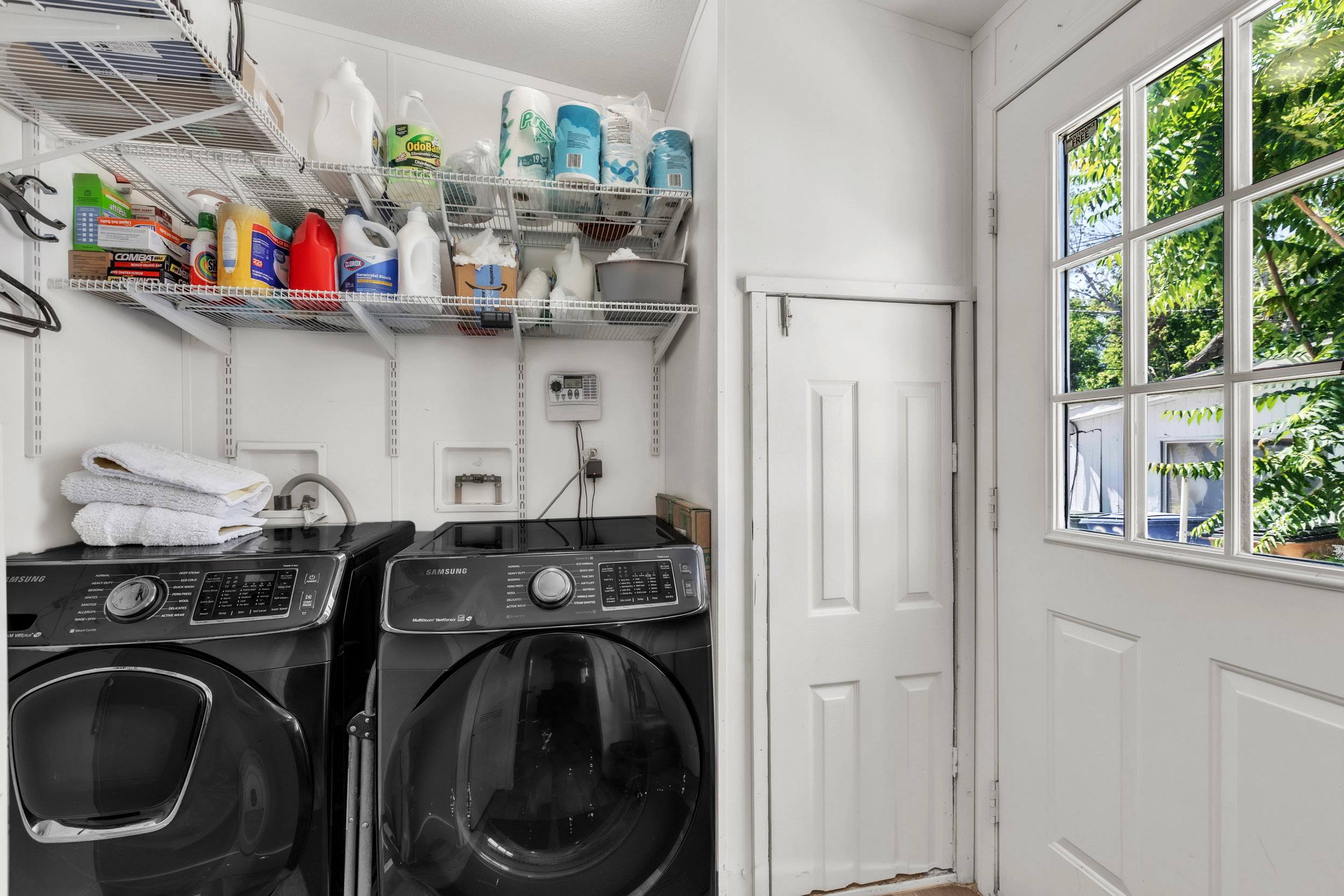Utility space featuring wire shelving systems, white paneled walls, and a multi-pane glass entry door