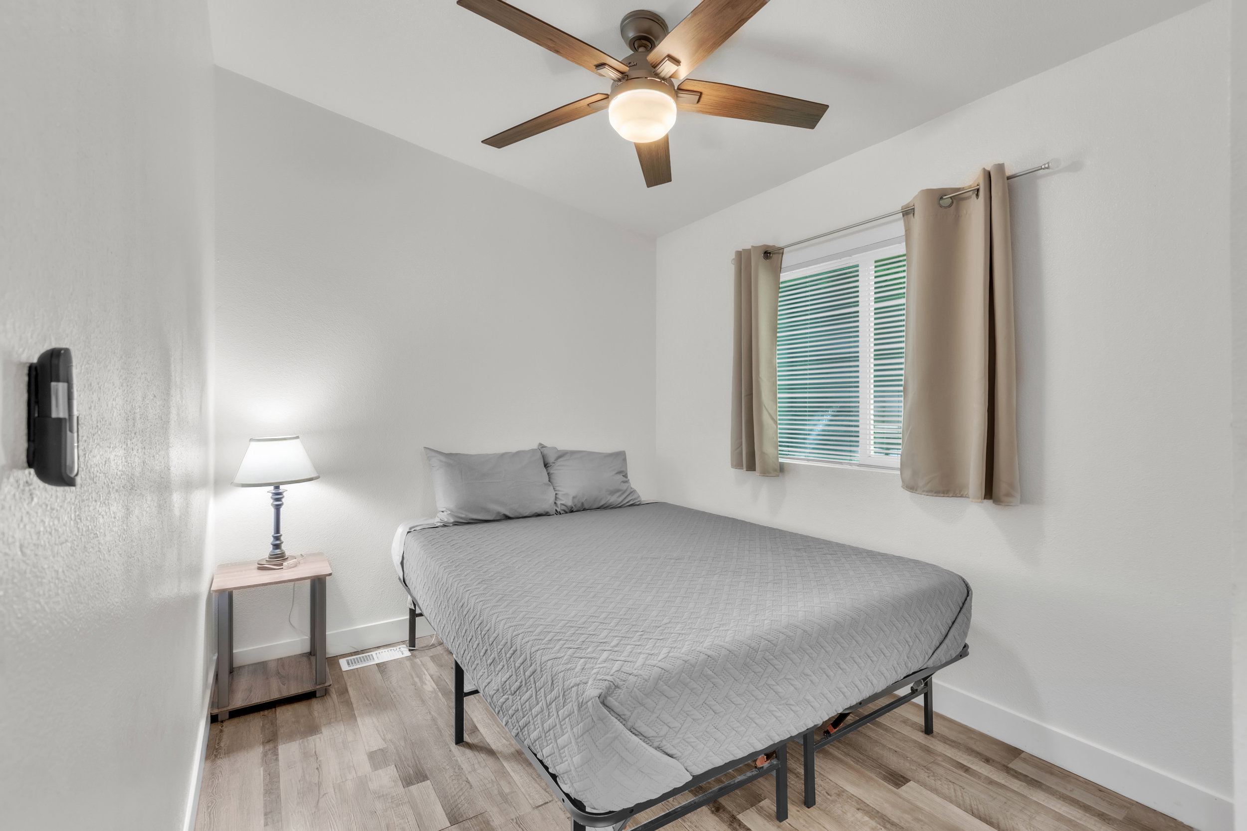 Room featuring light wood-finish flooring, a contemporary ceiling fan with integrated lighting, and a window with blinds