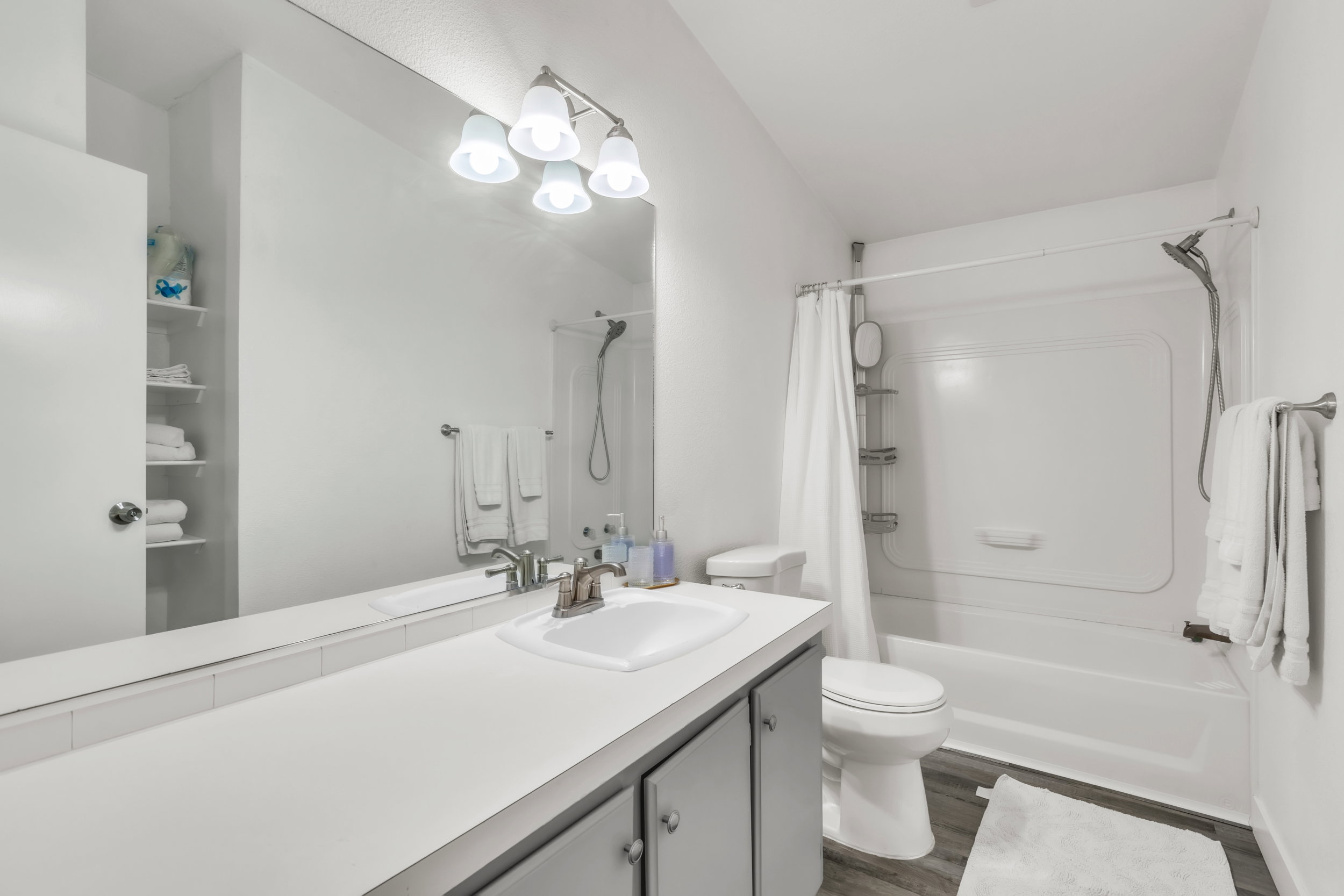 Bathroom featuring a white vanity with an integrated sink, brushed nickel faucet, and full-width mirror
