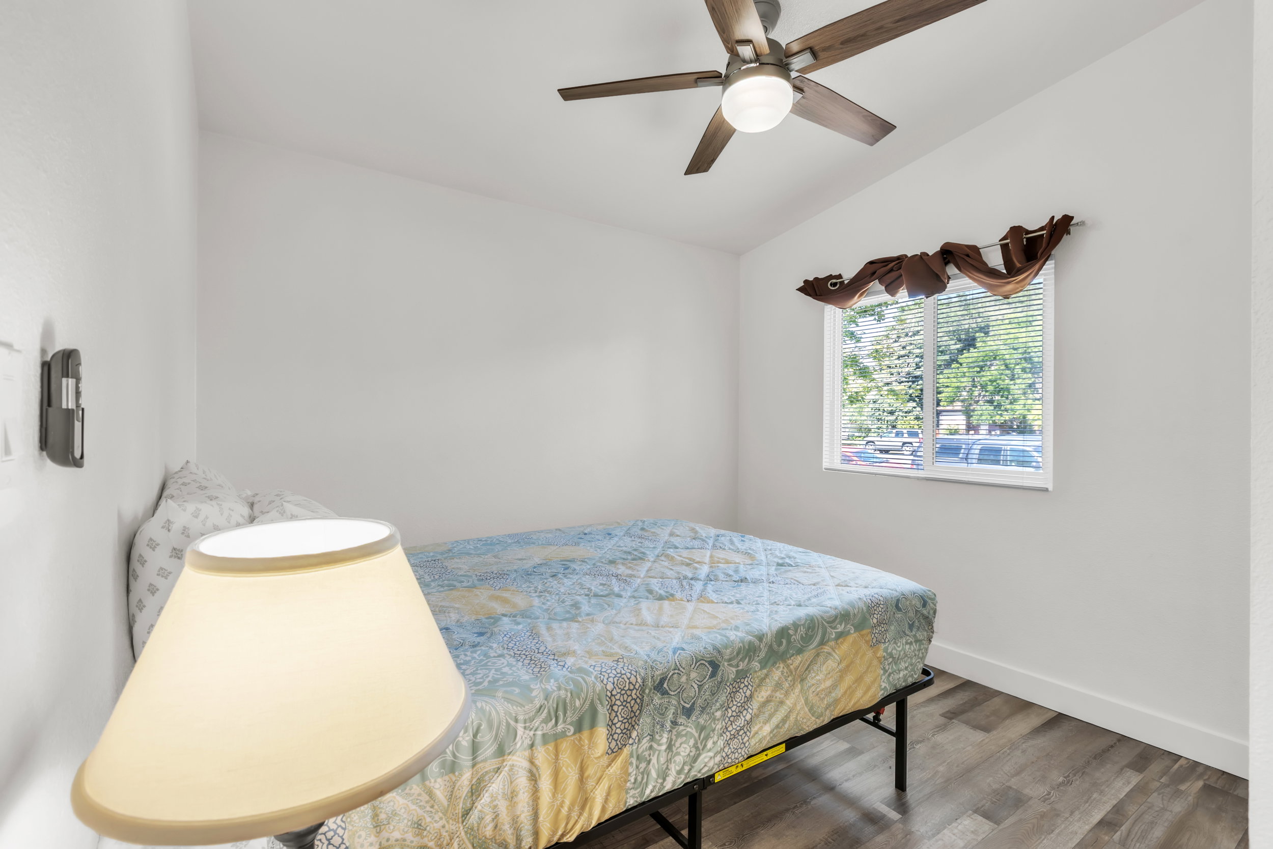 Room featuring wood-finish flooring, a window with horizontal blinds, and a ceiling fan with integrated lighting