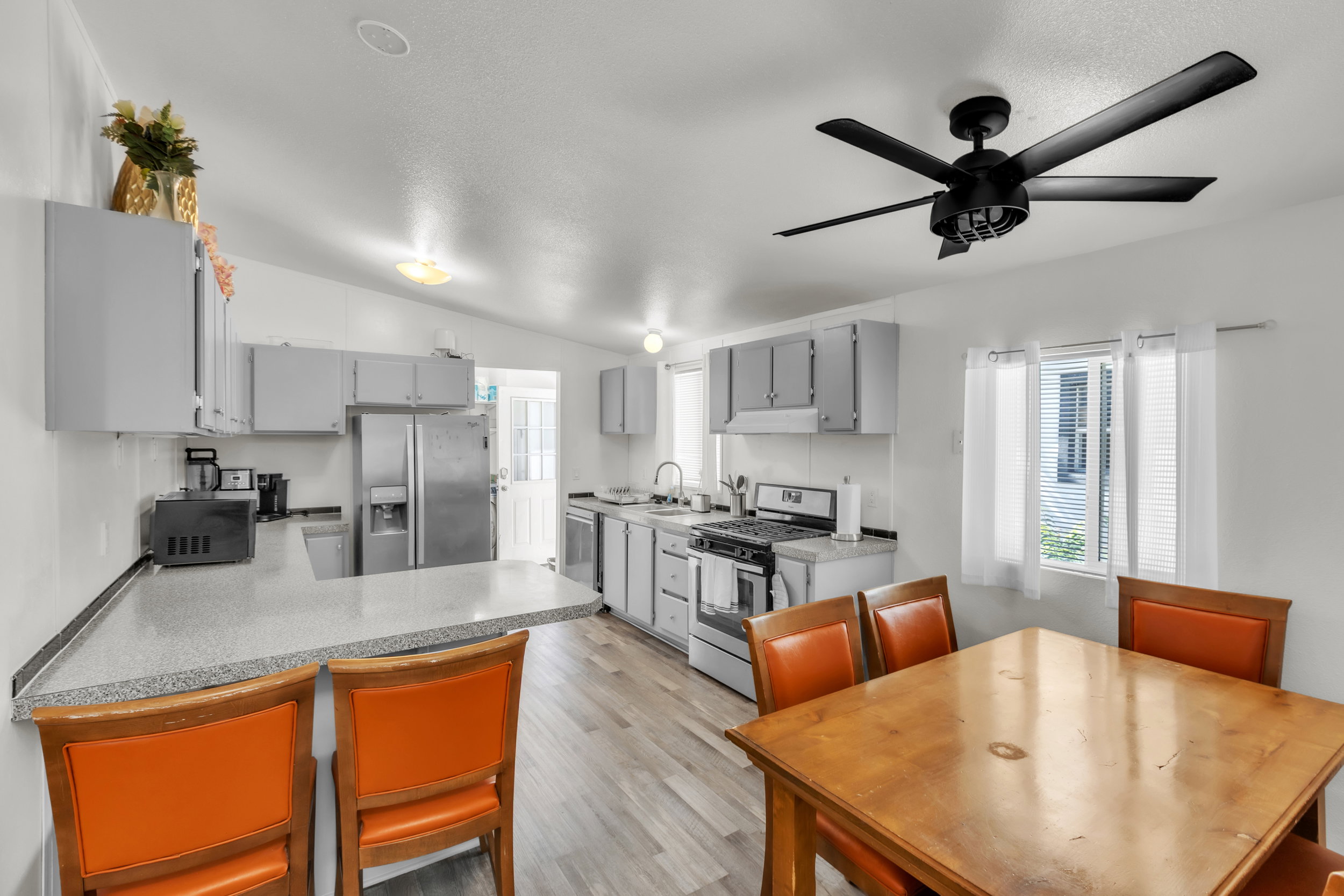 Spacious kitchen with wood-finish flooring, light grey cabinetry, and a peninsula with countertop seating