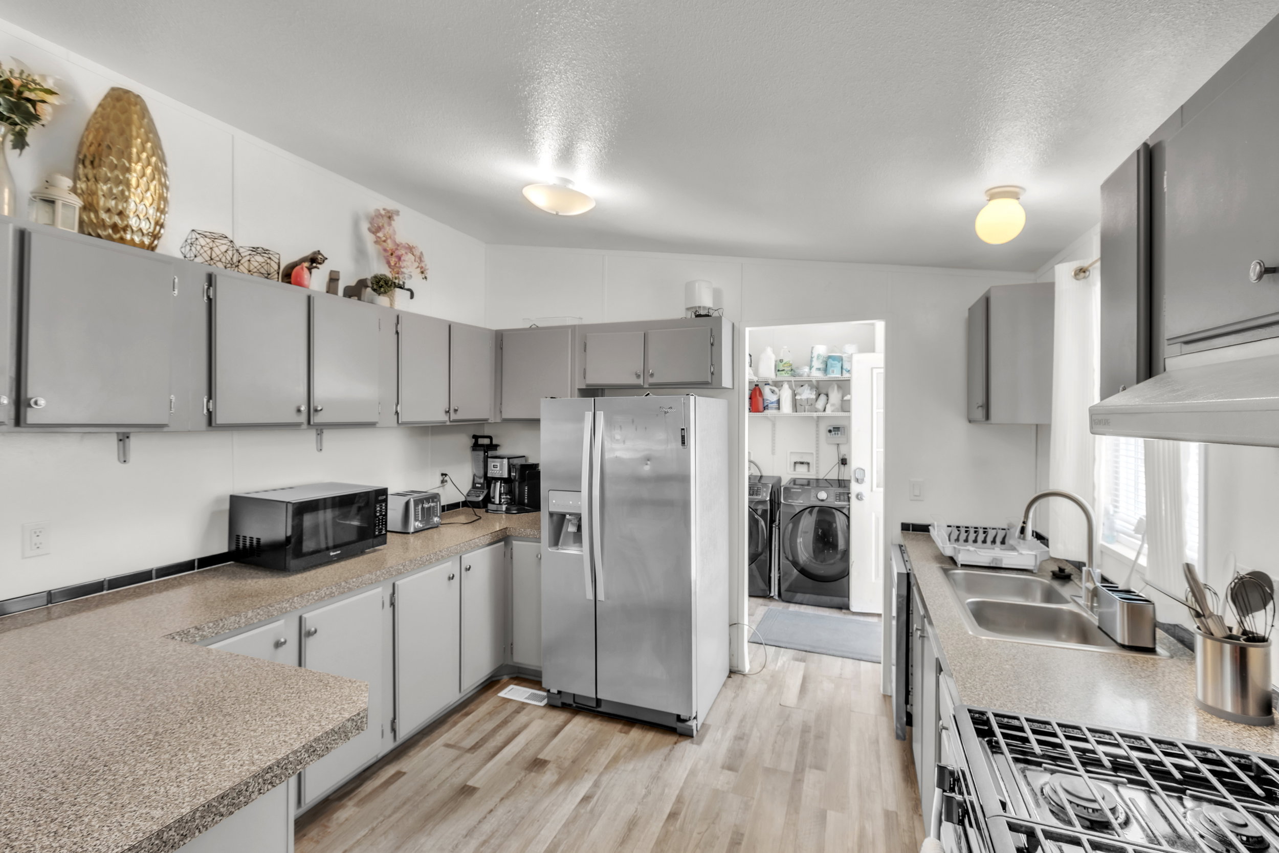 Kitchen featuring wood-finish flooring, light-toned countertops, grey cabinetry, and a double basin stainless steel sink