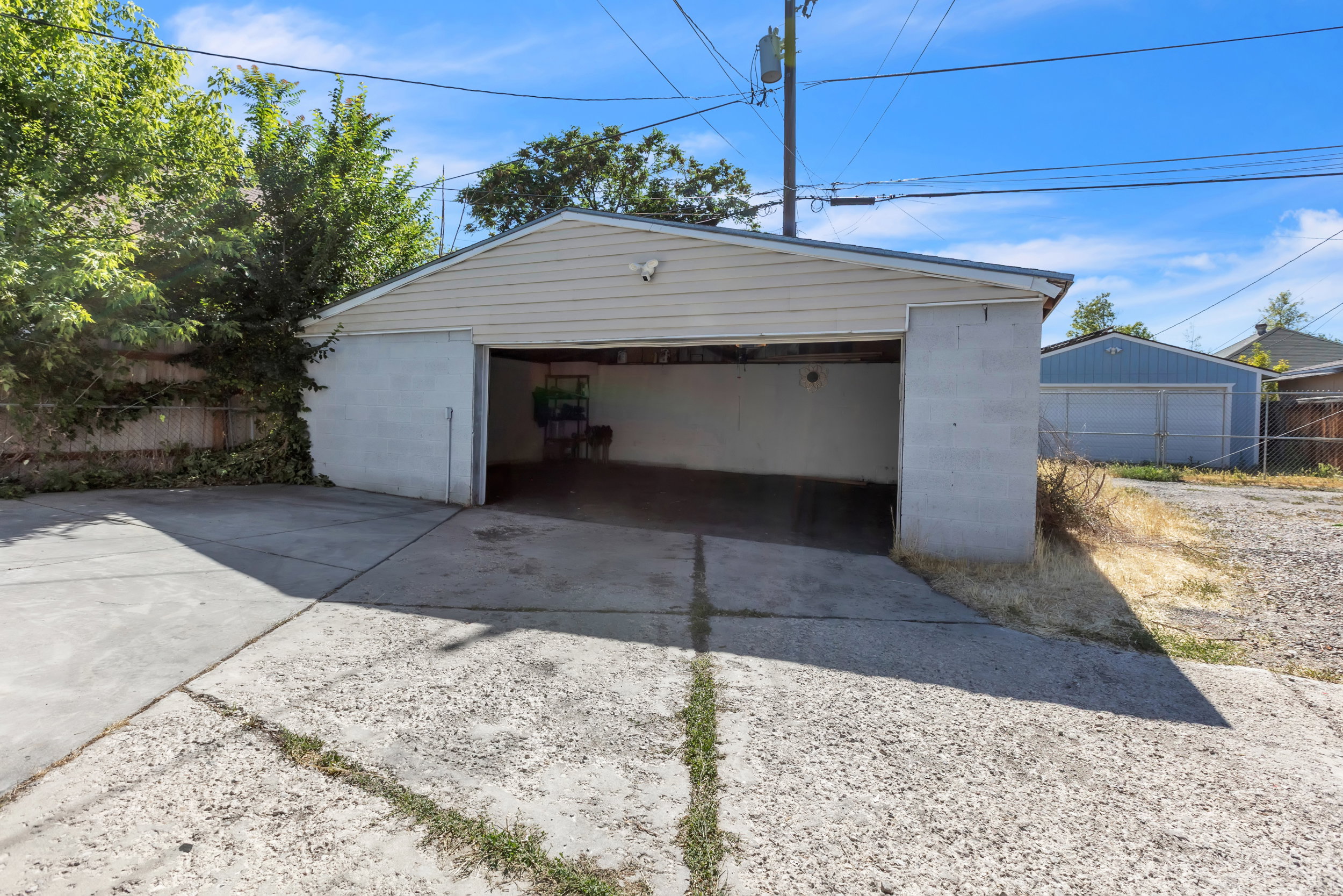 Detached garage with an open bay and concrete pad