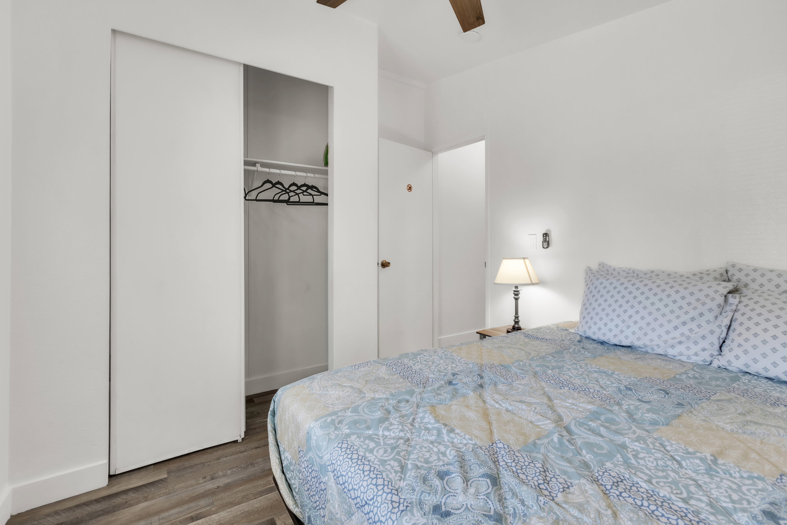 Bedroom featuring wood-finish flooring, a white ceiling with a ceiling fan, and a built-in closet with sliding doors and interior shelving