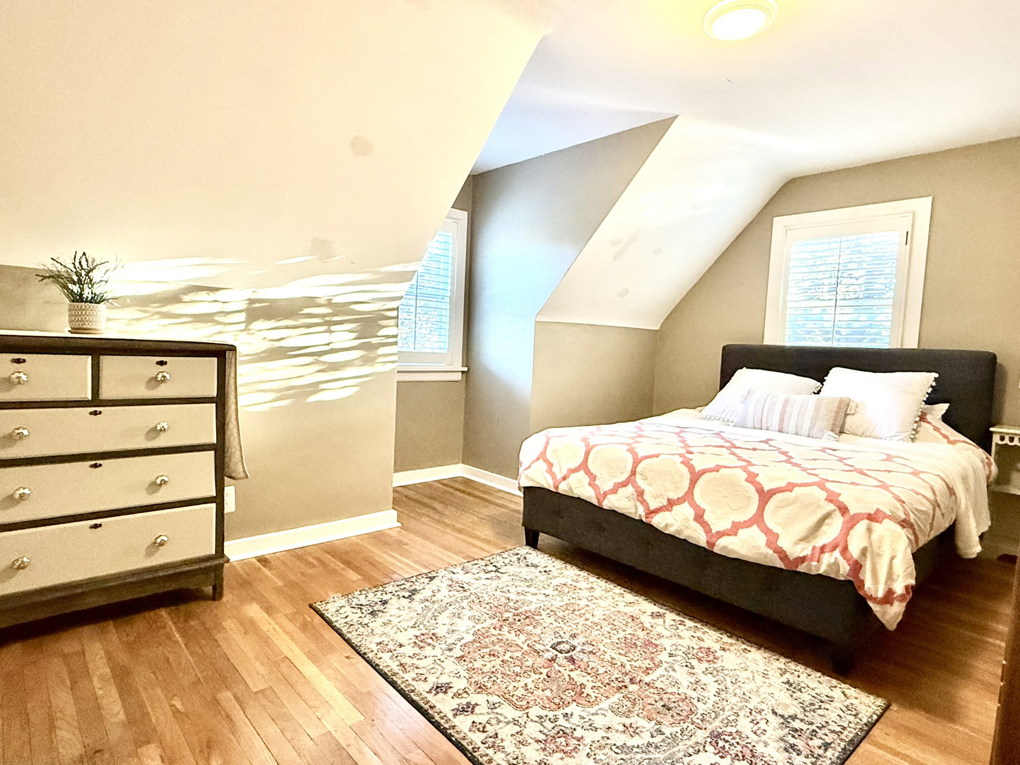 Bedroom #2  featuring wood-finish flooring, two windows, sloped ceilings, and a flush-mount ceiling light