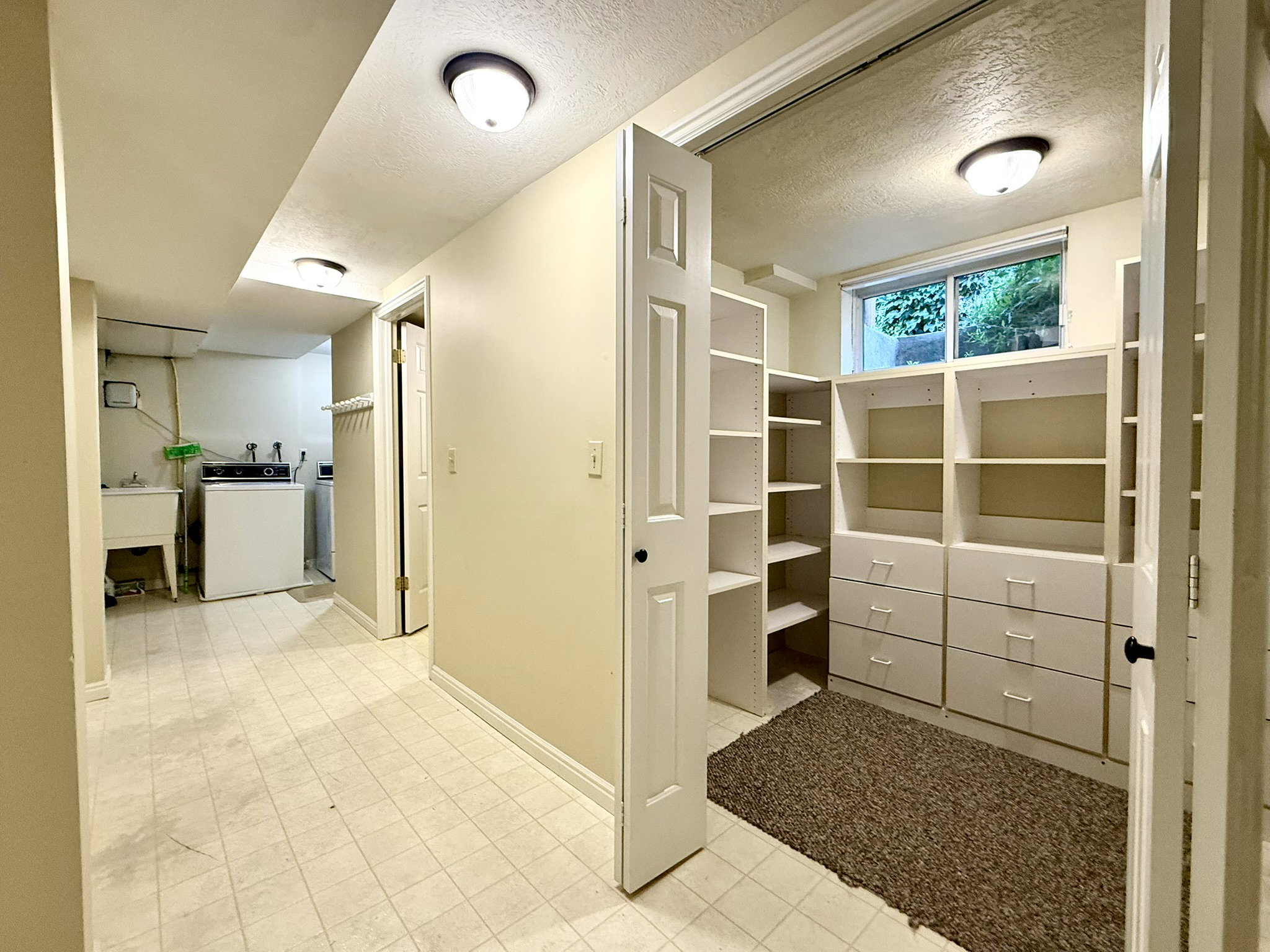 Interior utility space featuring a laundry area with a utility sink, a built-in washer and dryer, and a separate room with built-in shelving and drawers