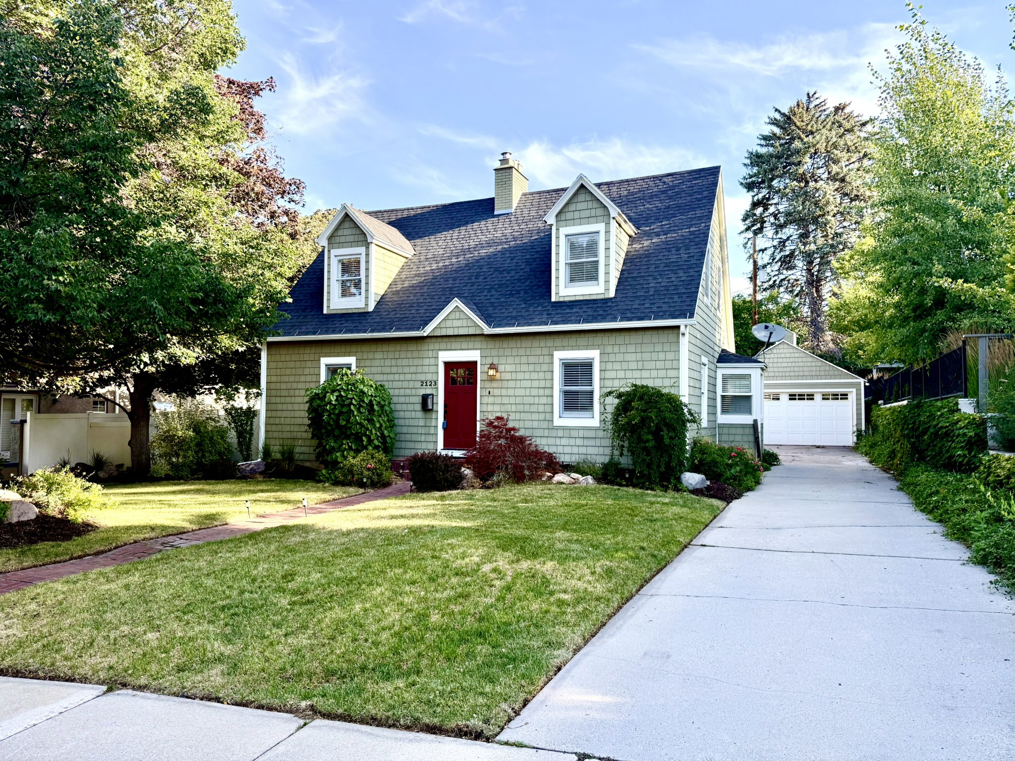 Gabled roofline with dormer windows atop a green shingle exterior