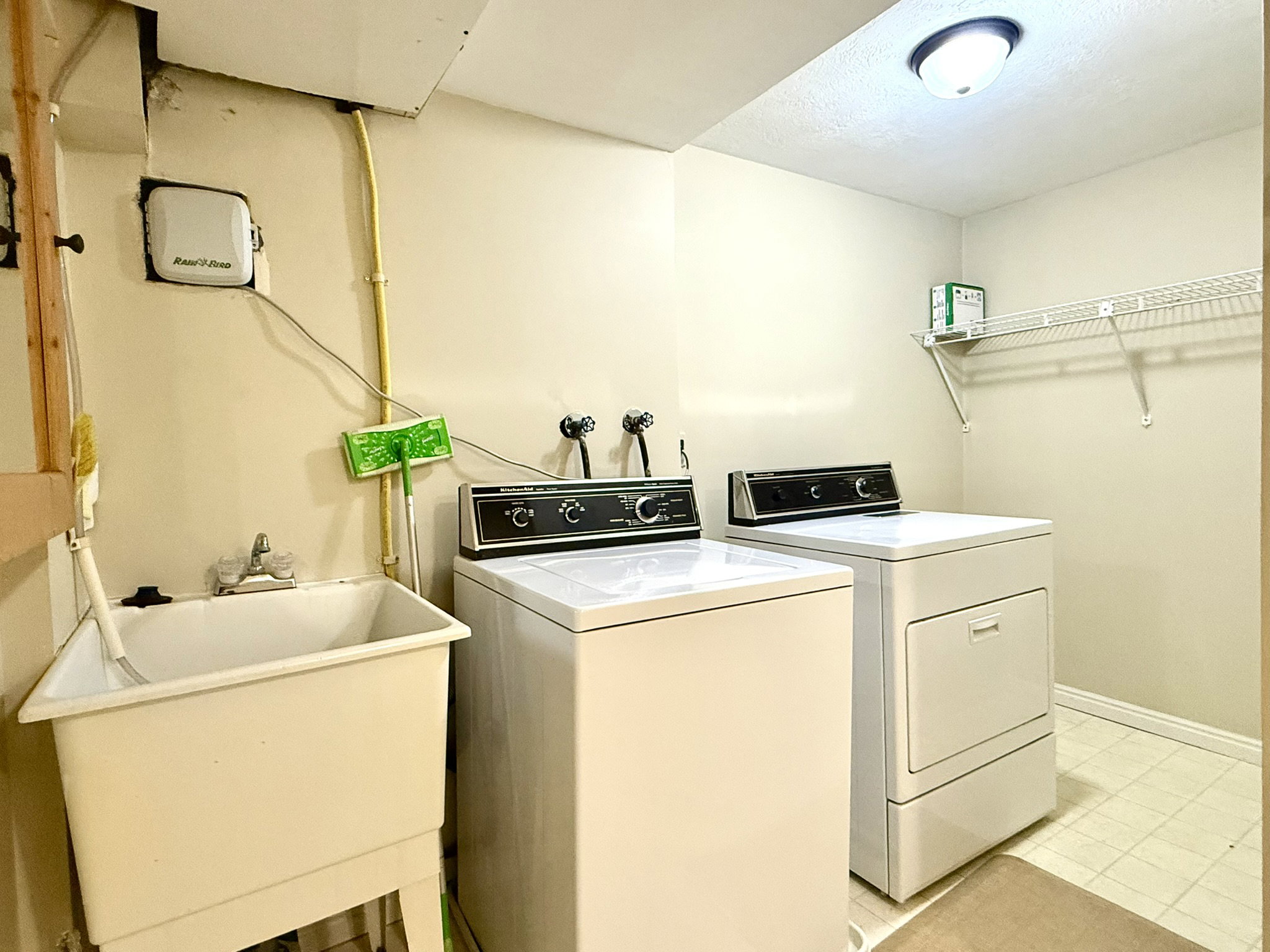 Dedicated laundry area featuring a utility sink with a chrome faucet, light-toned wall paint, and overhead lighting