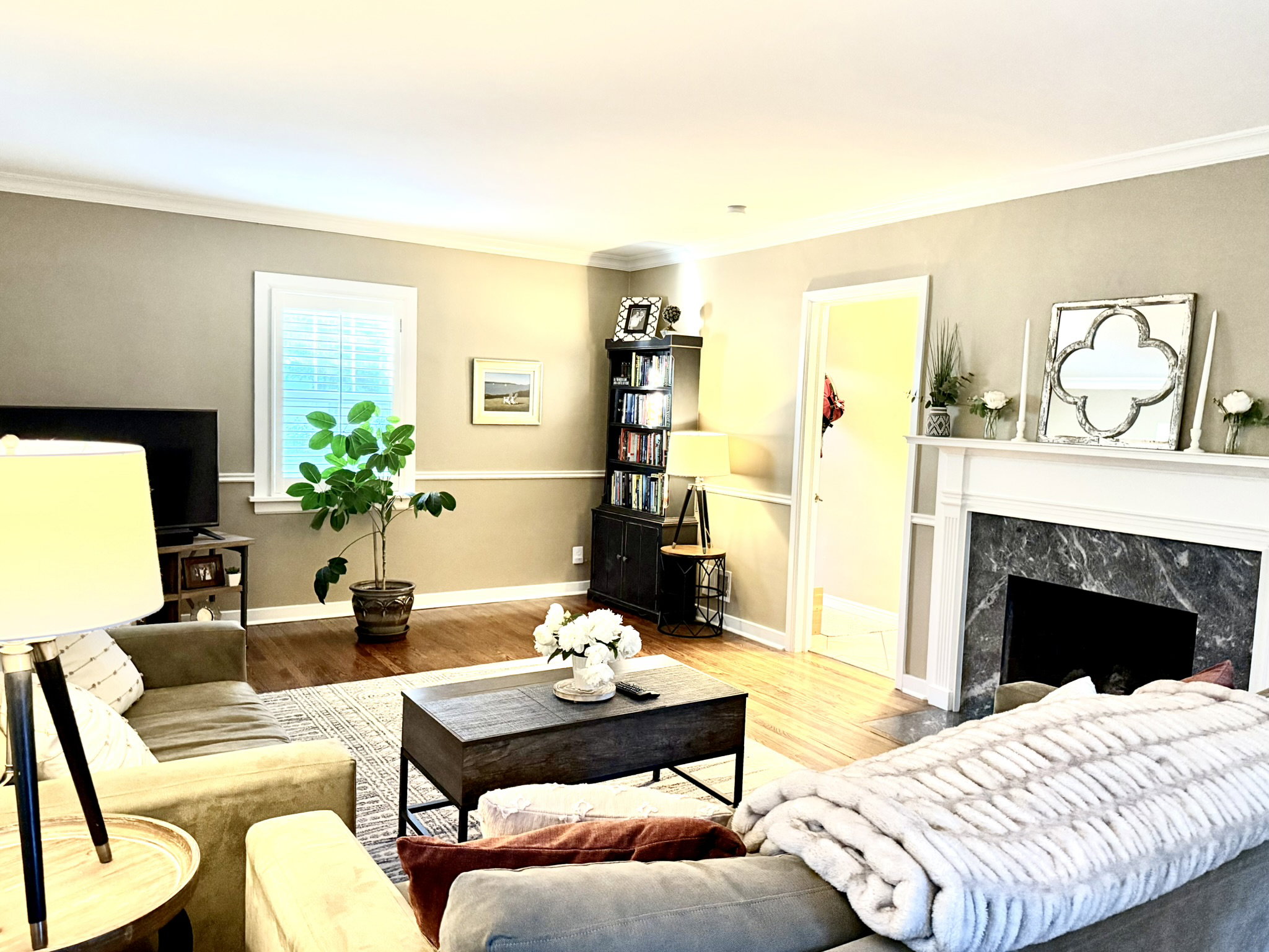 Living area with wood-finish flooring, a white-mantled fireplace, and dark-toned stone surround