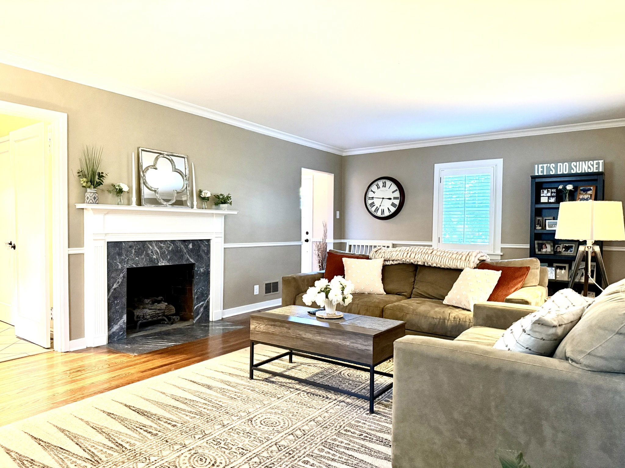 Living room featuring wood-finish flooring, a white mantel, and a dark stone fireplace surround