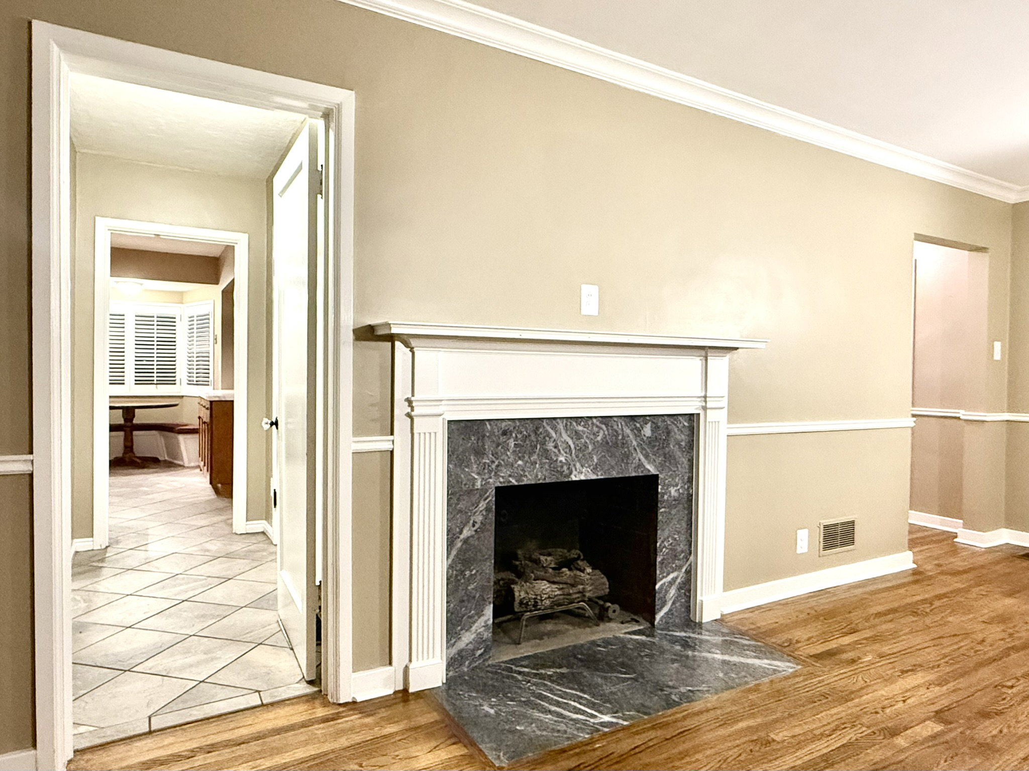 Living area featuring a classic fireplace with a stone surround and hearth, wood-finish flooring, and crown molding