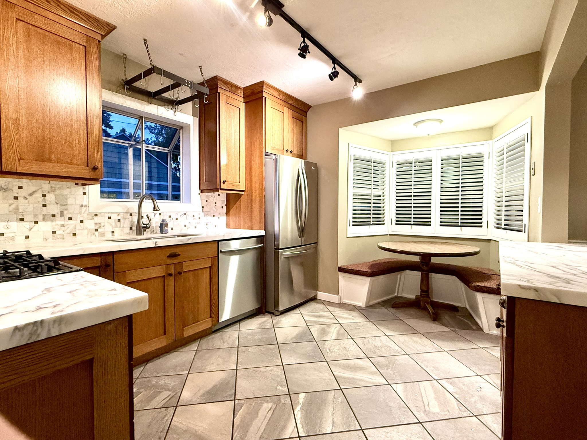 Kitchen featuring wood cabinetry, stainless steel appliances, a tile backsplash, and stone countertops
