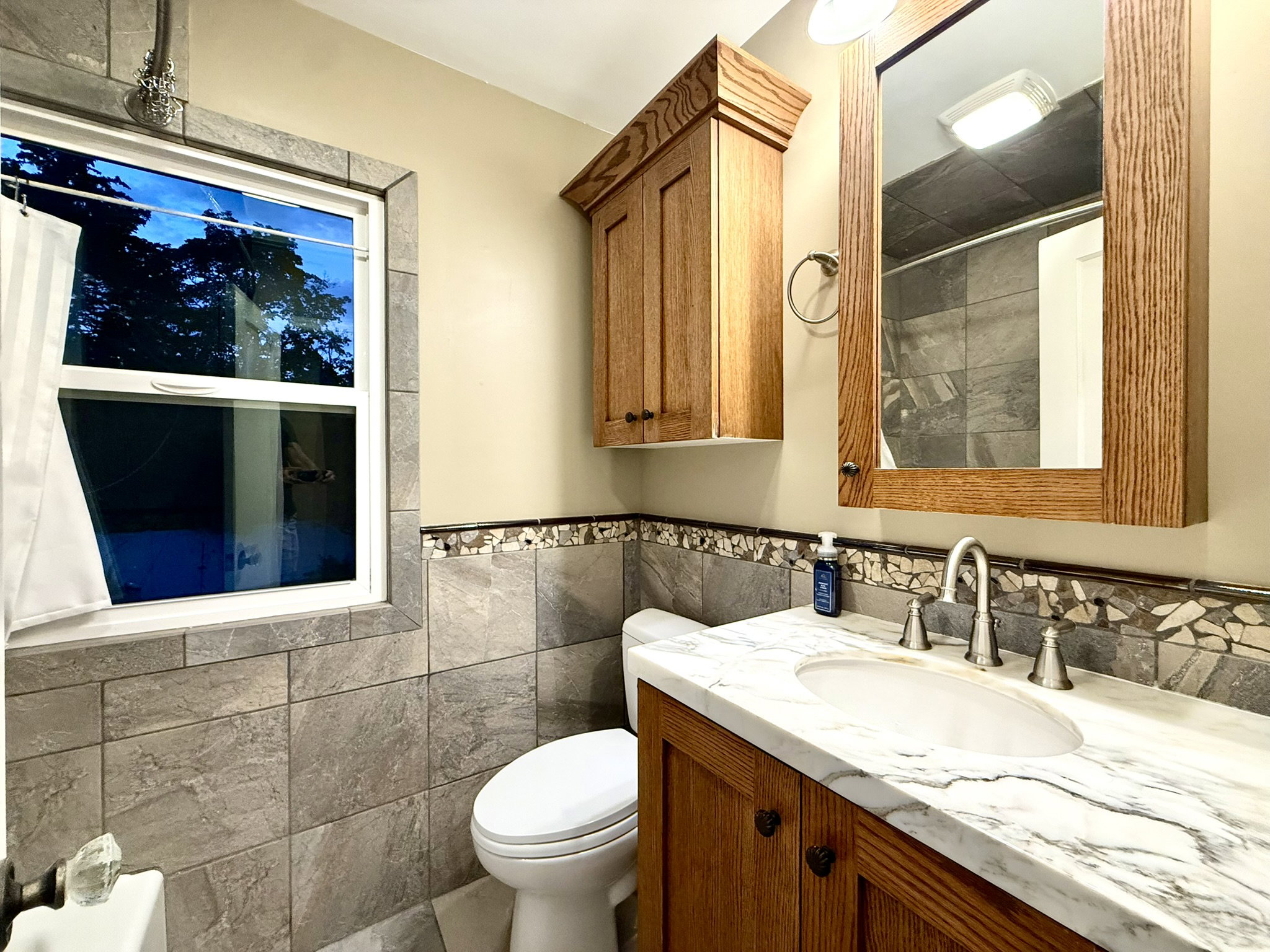 UL Bathroom featuring a marble-finish countertop vanity with an undermount sink, wood-finish cabinetry, and a framed mirror