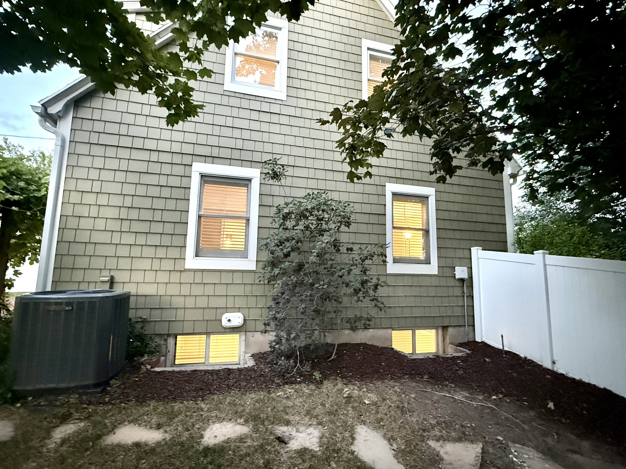 Shingle siding exterior with white trim windows and a white vinyl privacy fence
