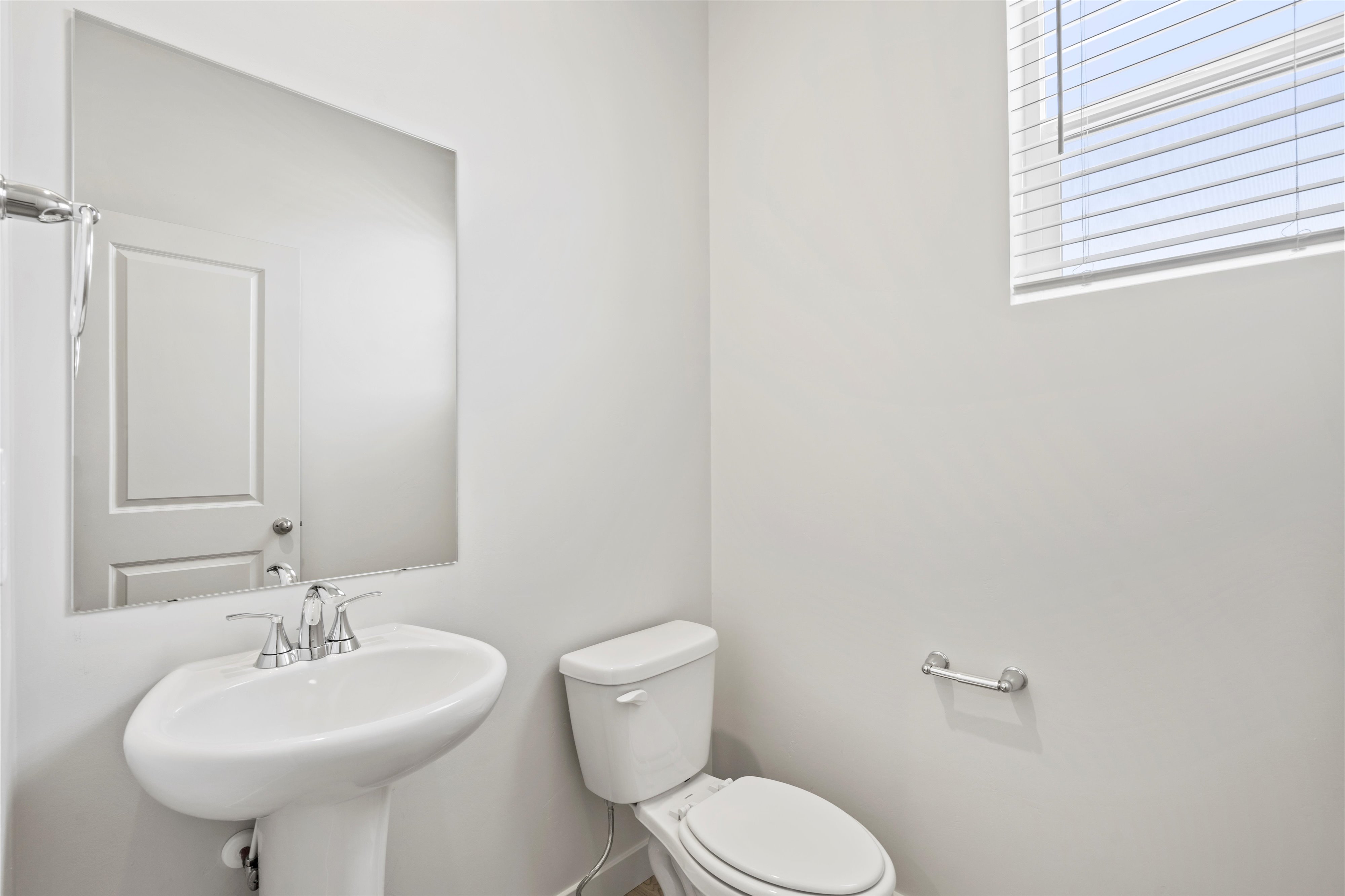 **DISCLAIMER** Interior package may vary. Pedestal sink with chrome faucet, wall-mounted mirror, and white toilet