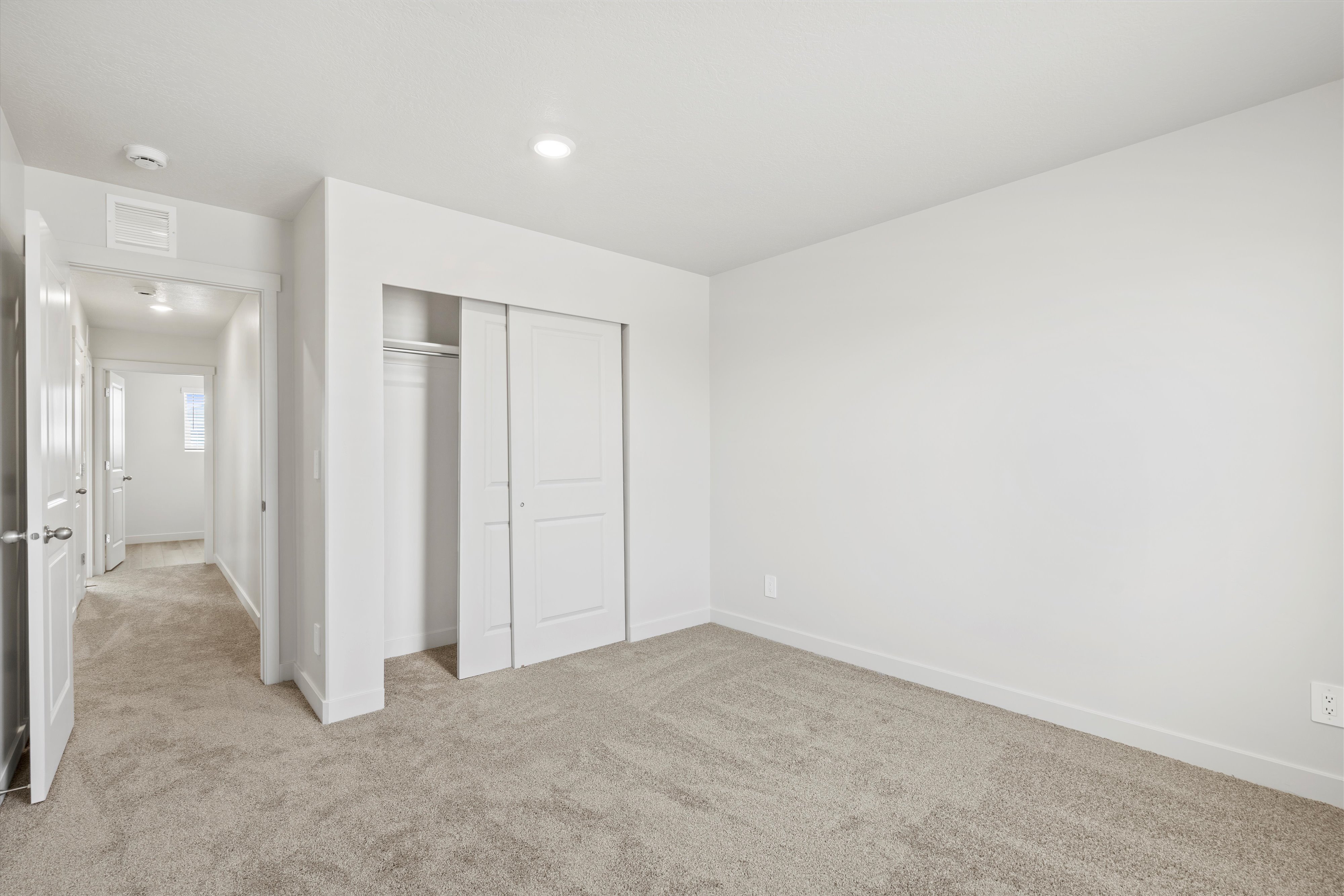 **DISCLAIMER** Interior package may vary. Spacious room featuring neutral carpeting, a large closet with sliding doors, and recessed ceiling lighting