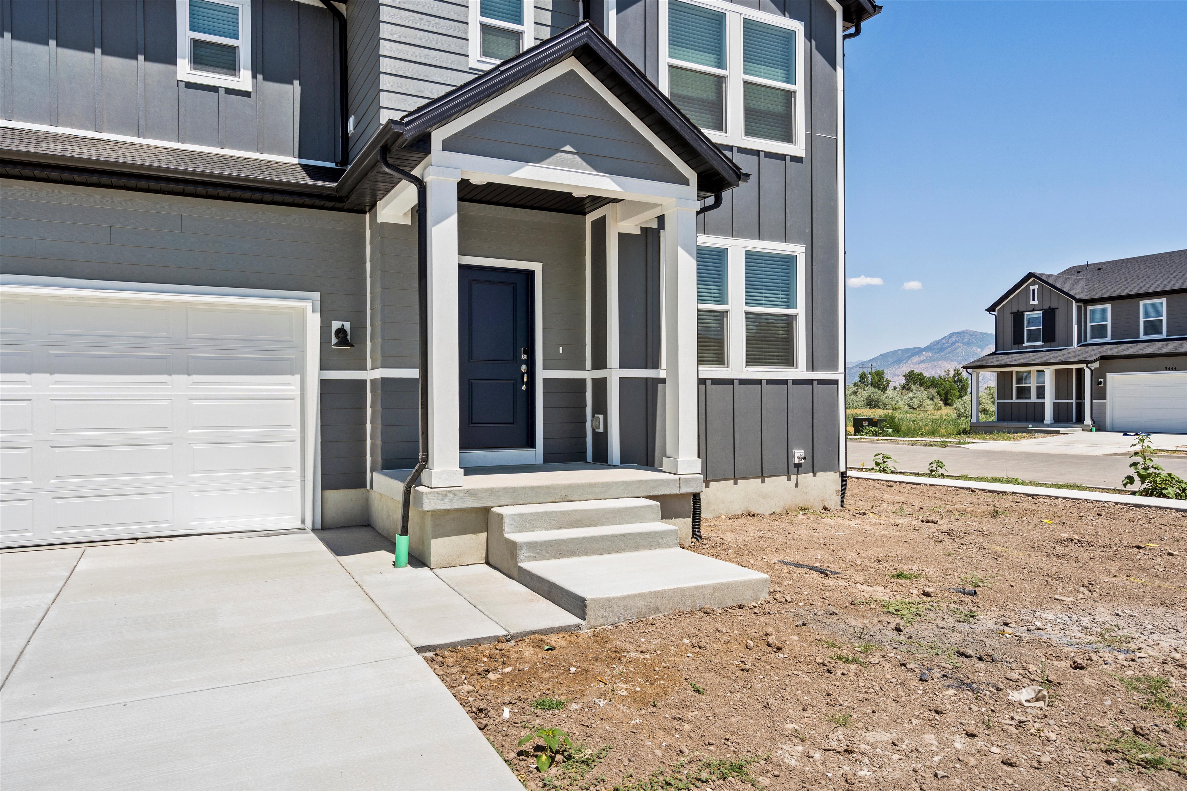 Contemporary exterior featuring vertical siding, a covered front entry with white columns, a dark panel door, a concrete driveway, and a two-car garage