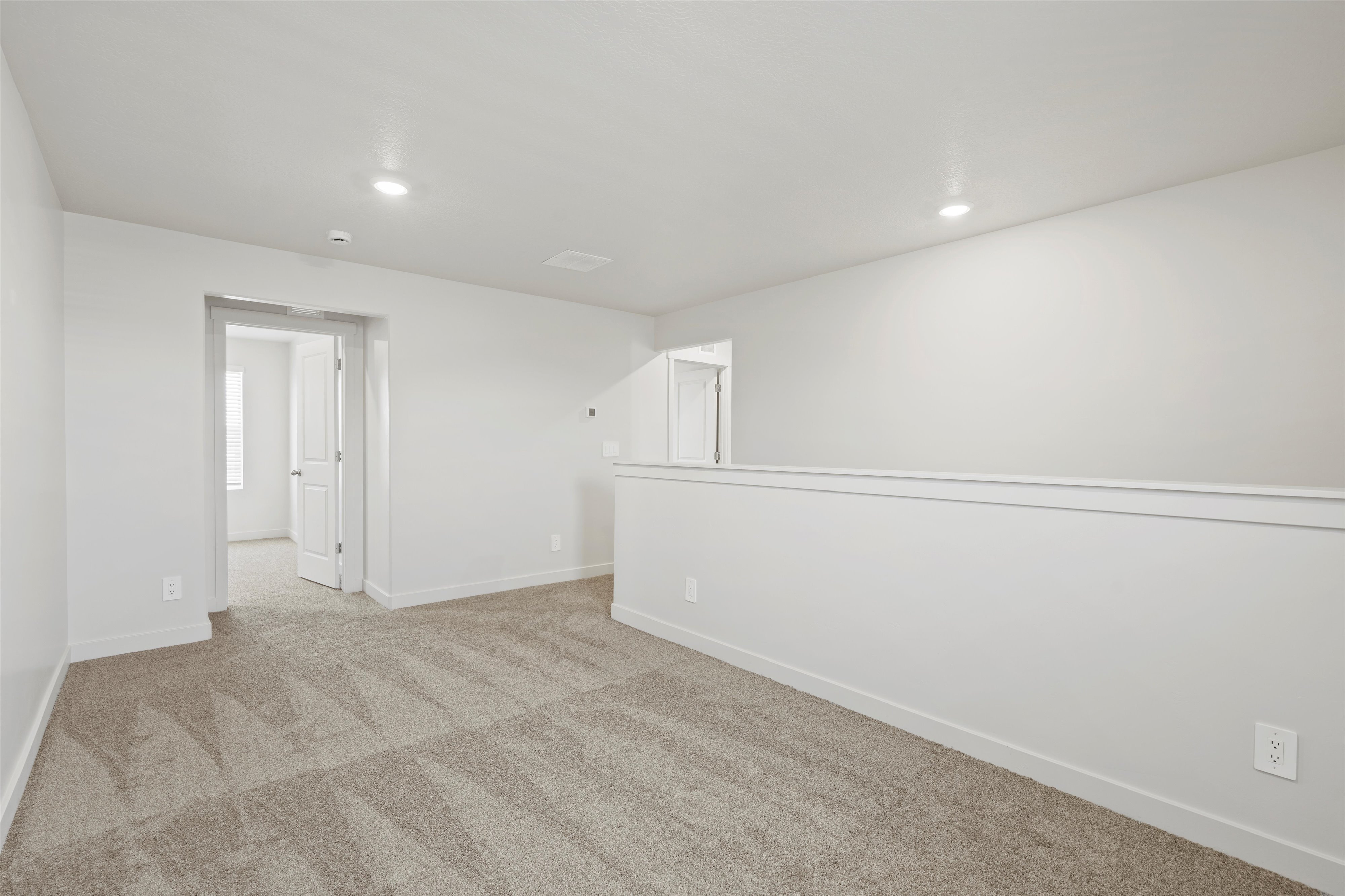 **DISCLAIMER** Interior package may vary. Spacious loft area featuring neutral-toned carpeting, recessed lighting, and a white half-wall railing