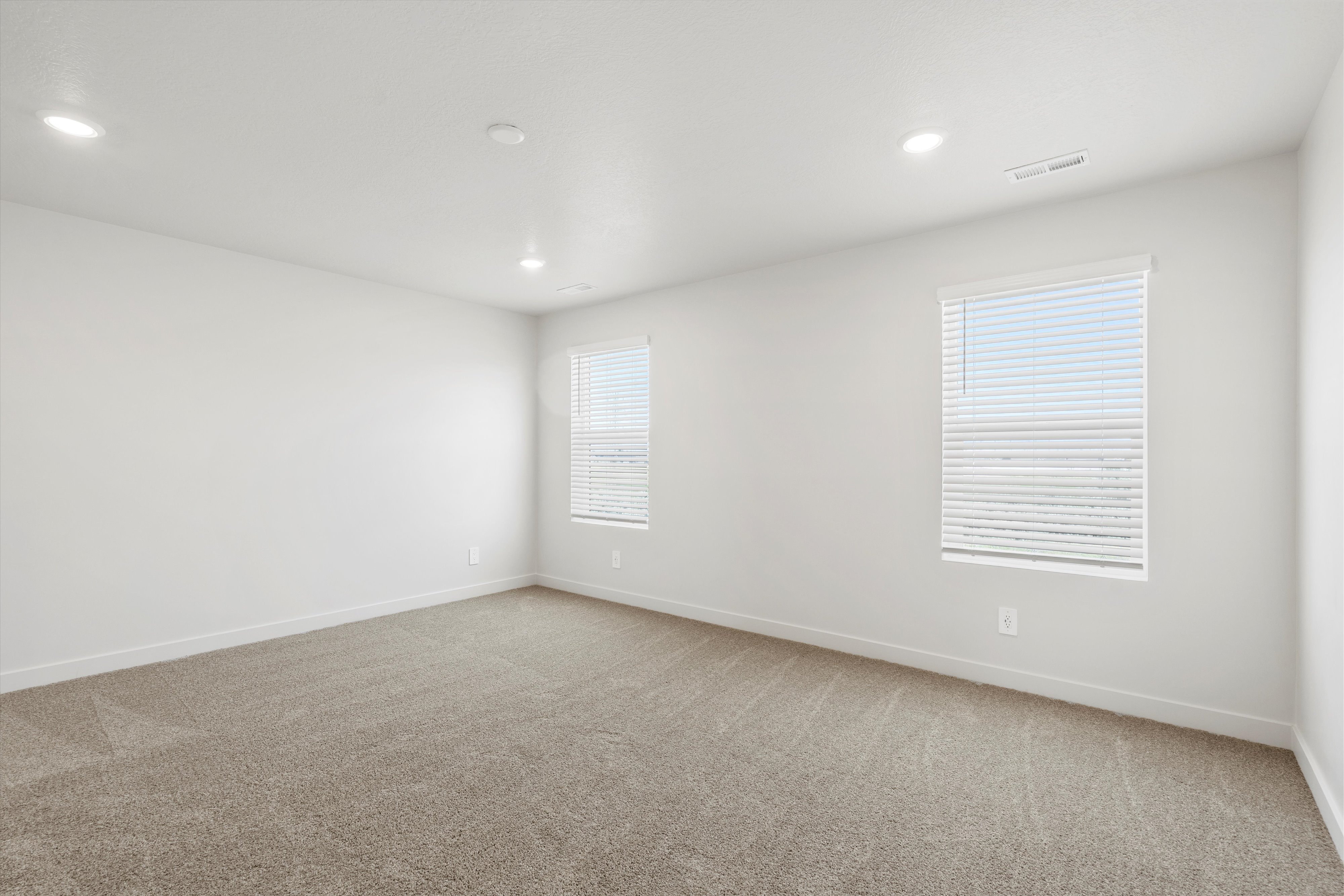 **DISCLAIMER** Interior package may vary. Spacious room featuring neutral carpeting, recessed lighting, and two windows with blinds