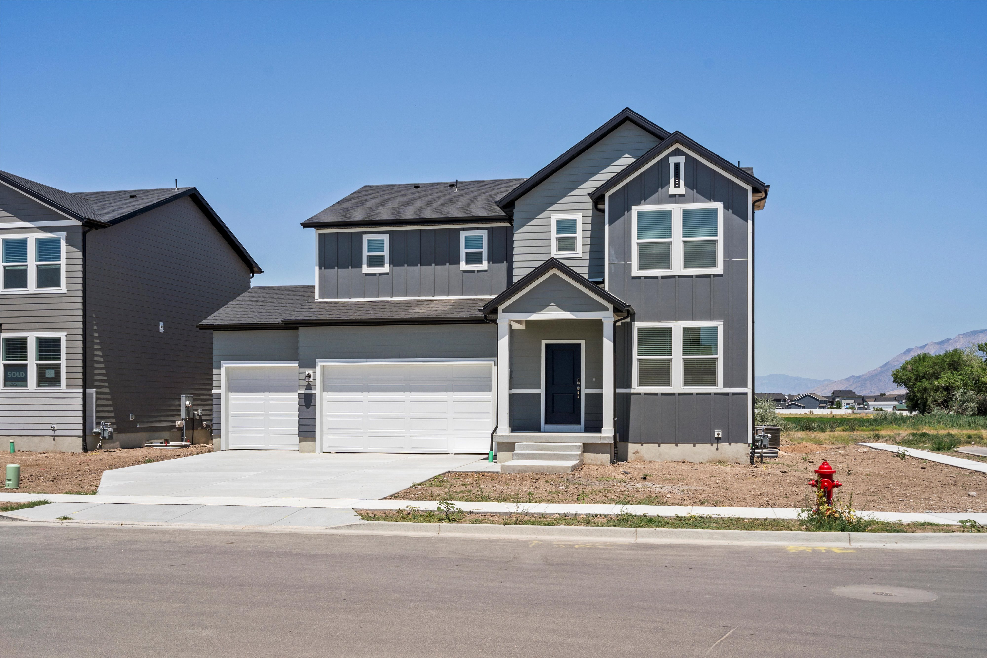 Contemporary two-story residence with a multi-tone gray facade, contrasting white trim, and a prominent covered entryway