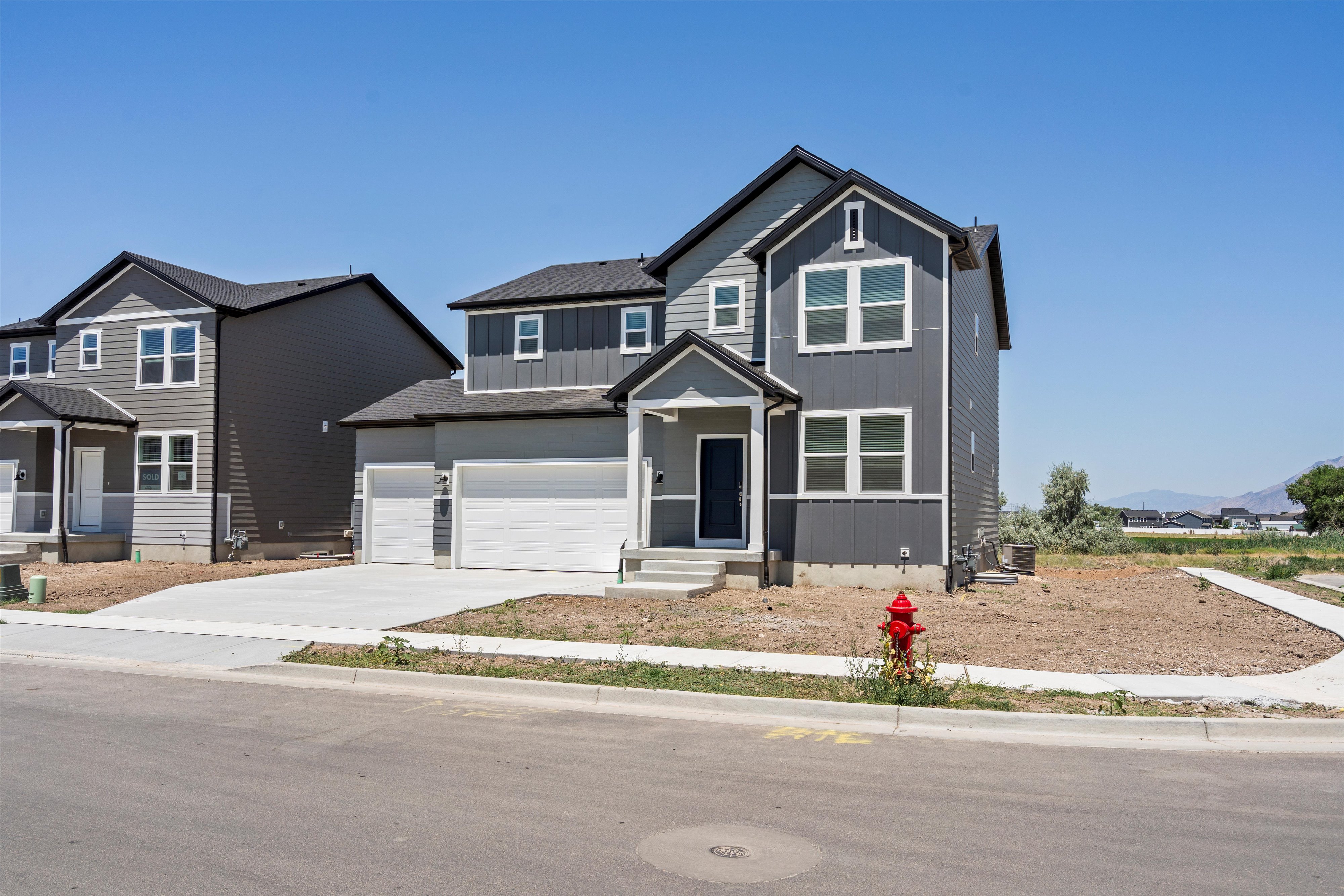 Contemporary two-story residence featuring a dark gray and light gray facade with vertical and horizontal siding