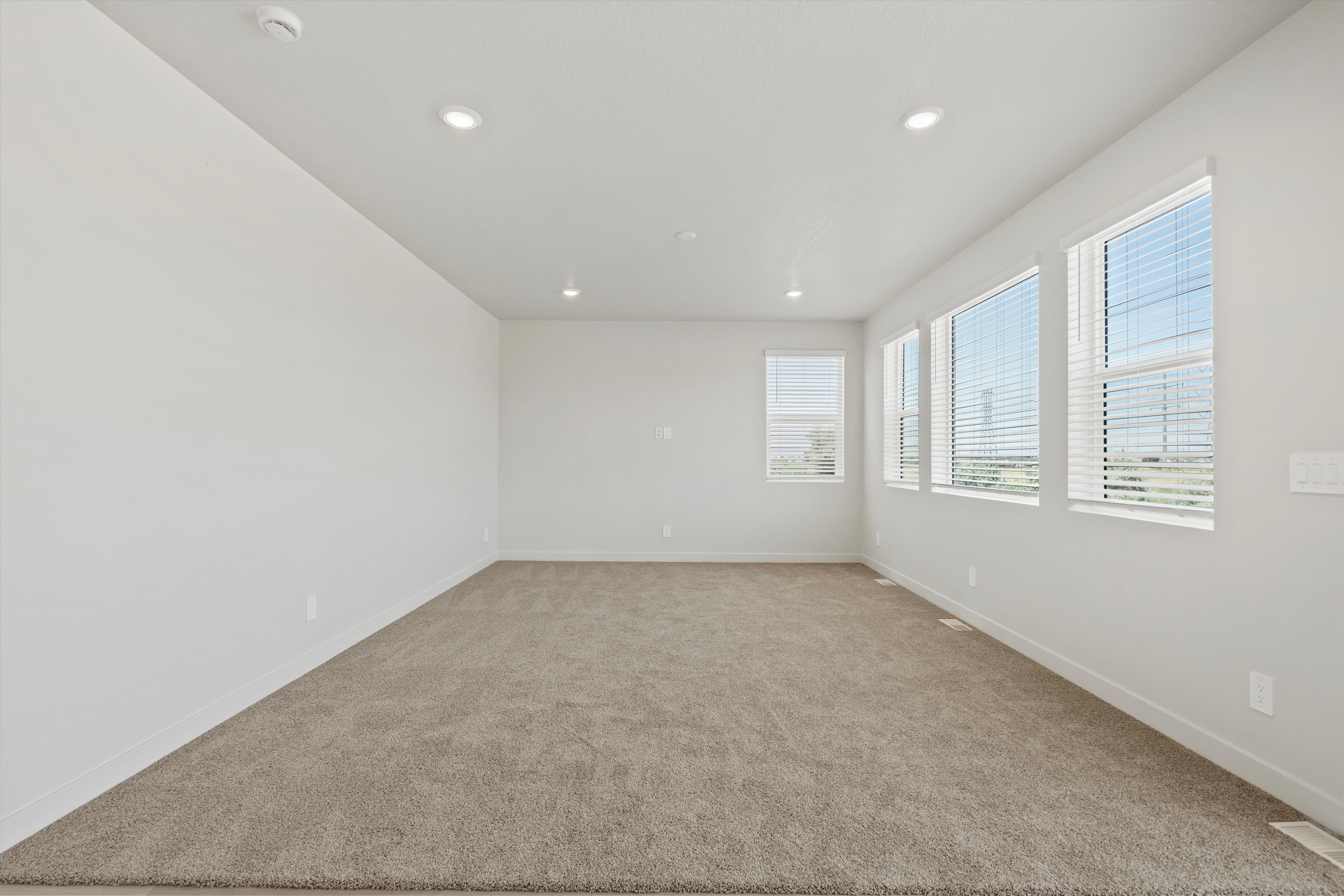 **DISCLAIMER** Interior package may vary. Spacious interior room featuring multiple windows with horizontal blinds, neutral wall finishes, and recessed ceiling lighting