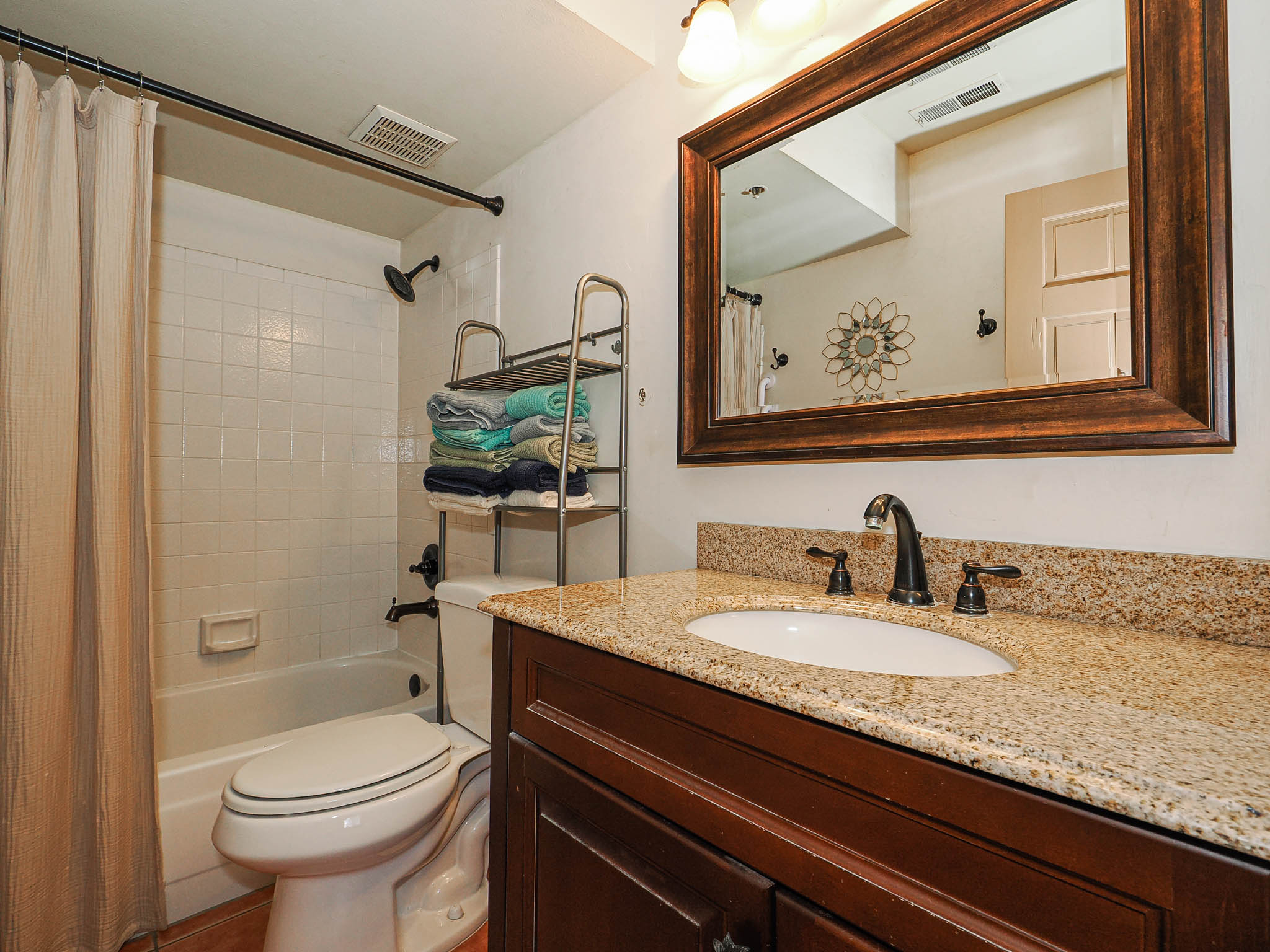 Bathroom vanity featuring a speckled countertop, undermount sink, and dark bronze-finish fixtures
