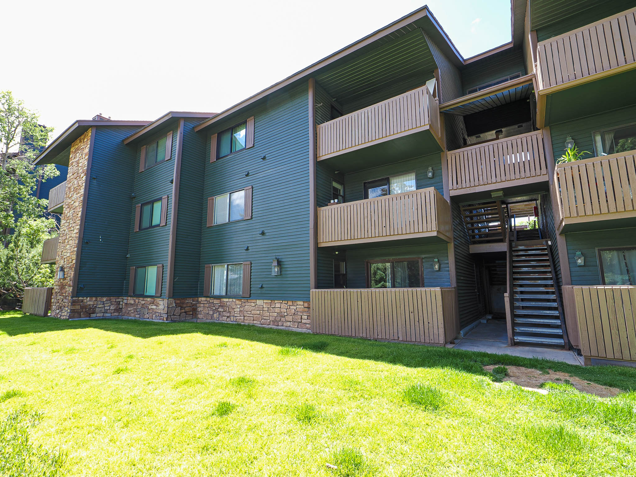 Multi-story building featuring dark green siding and stone veneer accents