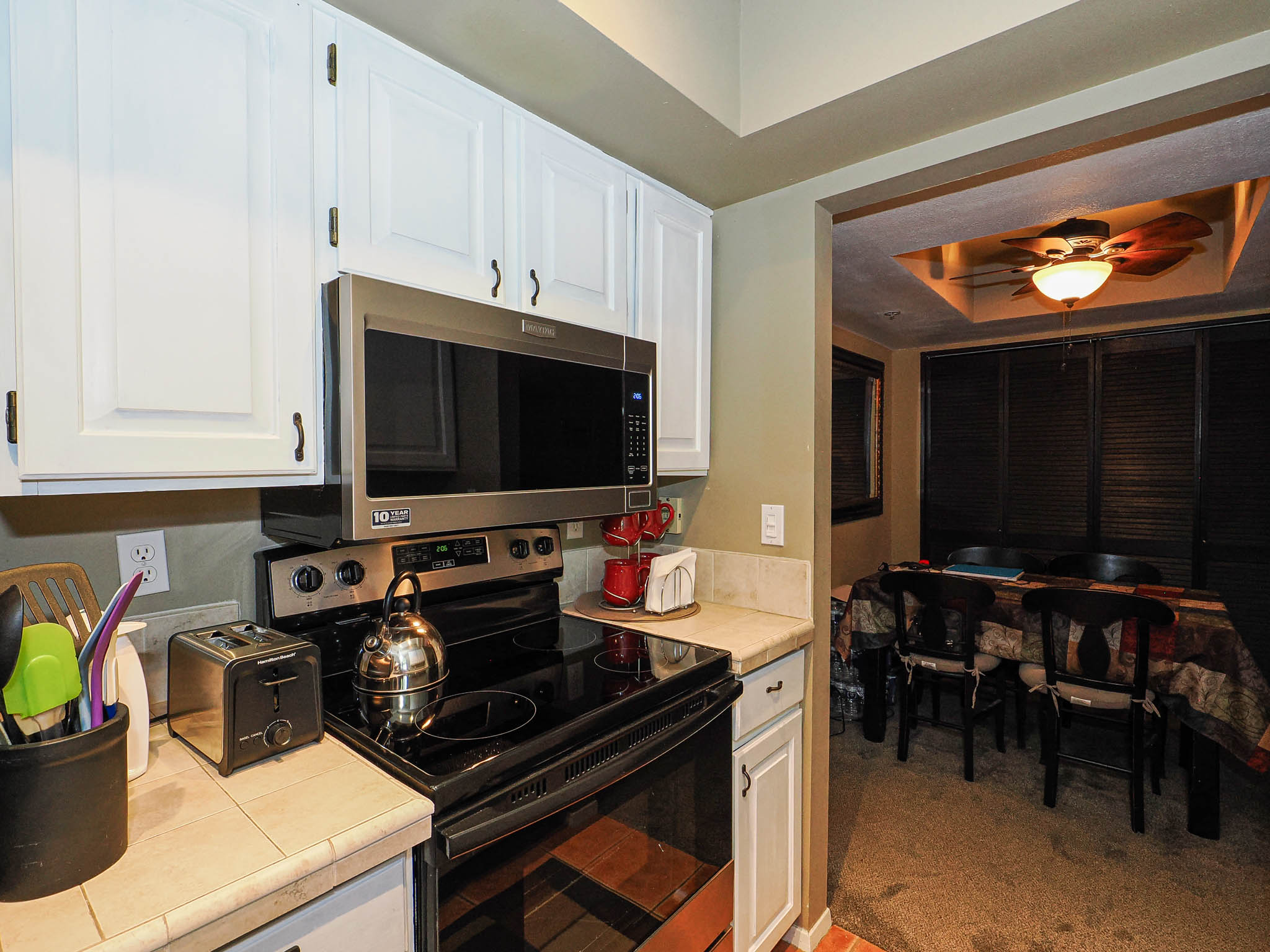 Kitchen area featuring white cabinetry, tile countertops, and a stainless steel over-the-range microwave