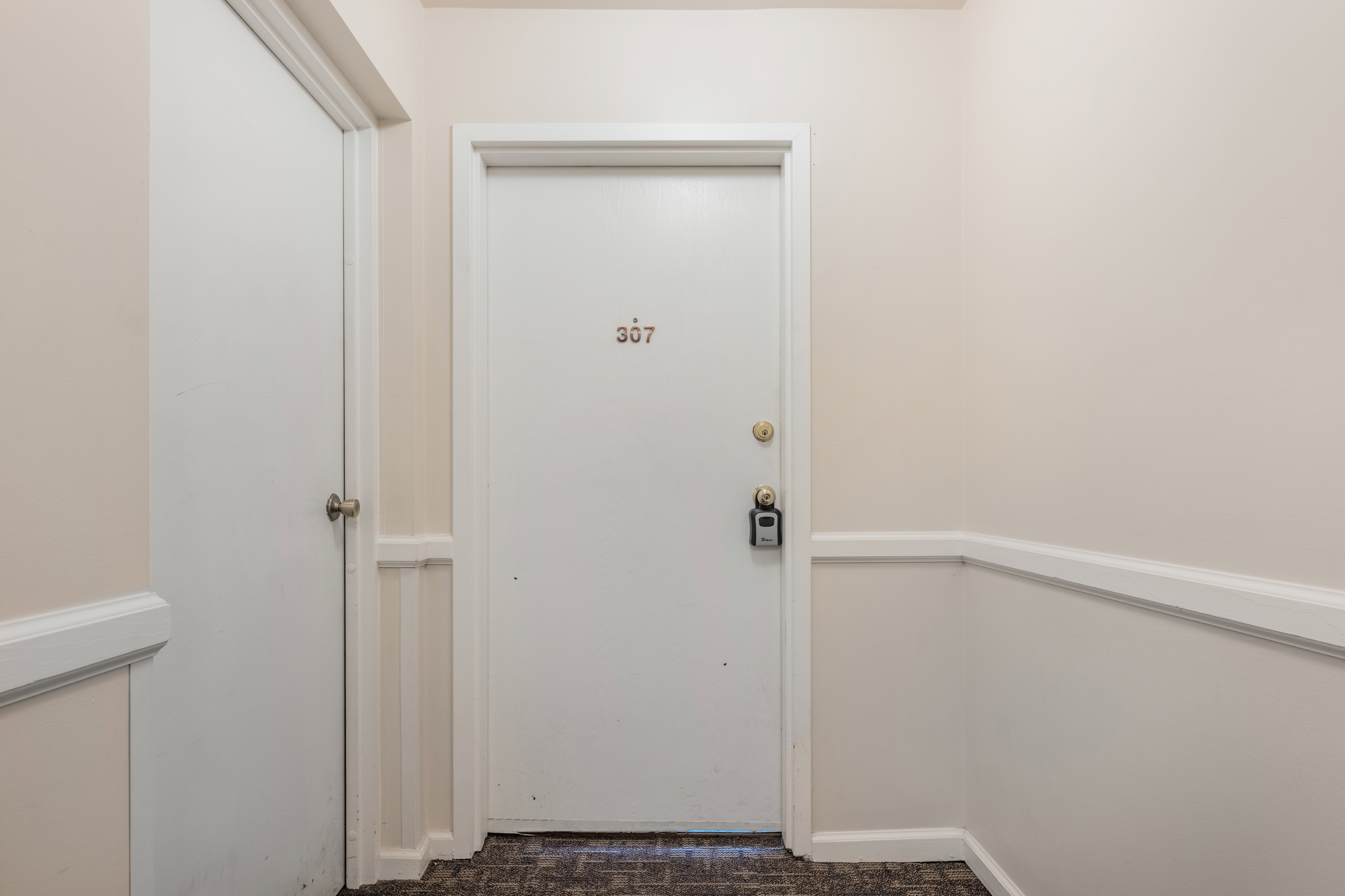 Property entry door featuring a brass handle and deadbolt, with room number 307