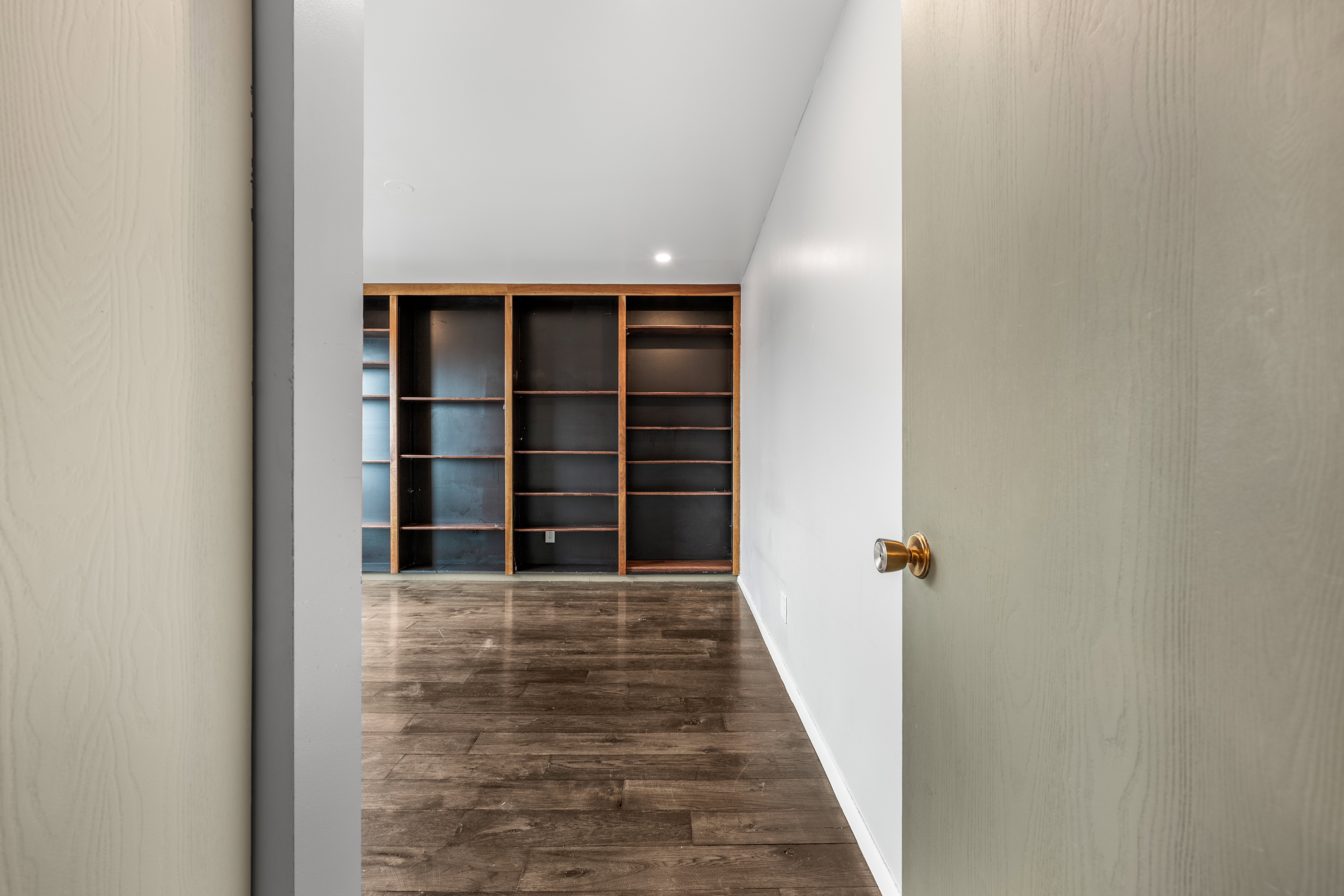 Room featuring extensive built-in shelving, wood-finish flooring, and recessed ceiling lighting