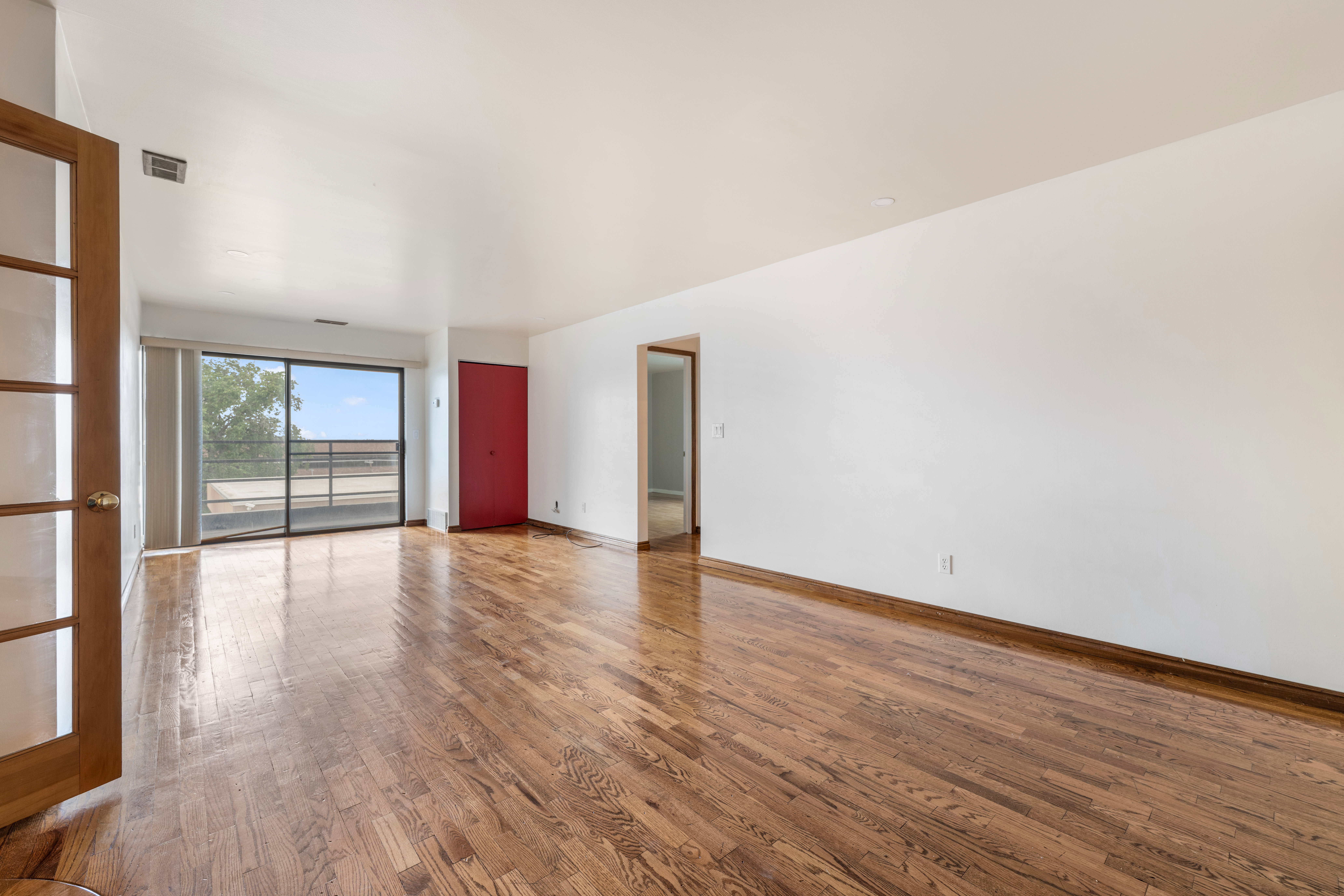Expansive living area featuring wood-finish flooring, a full-height glass sliding door, and a private balcony