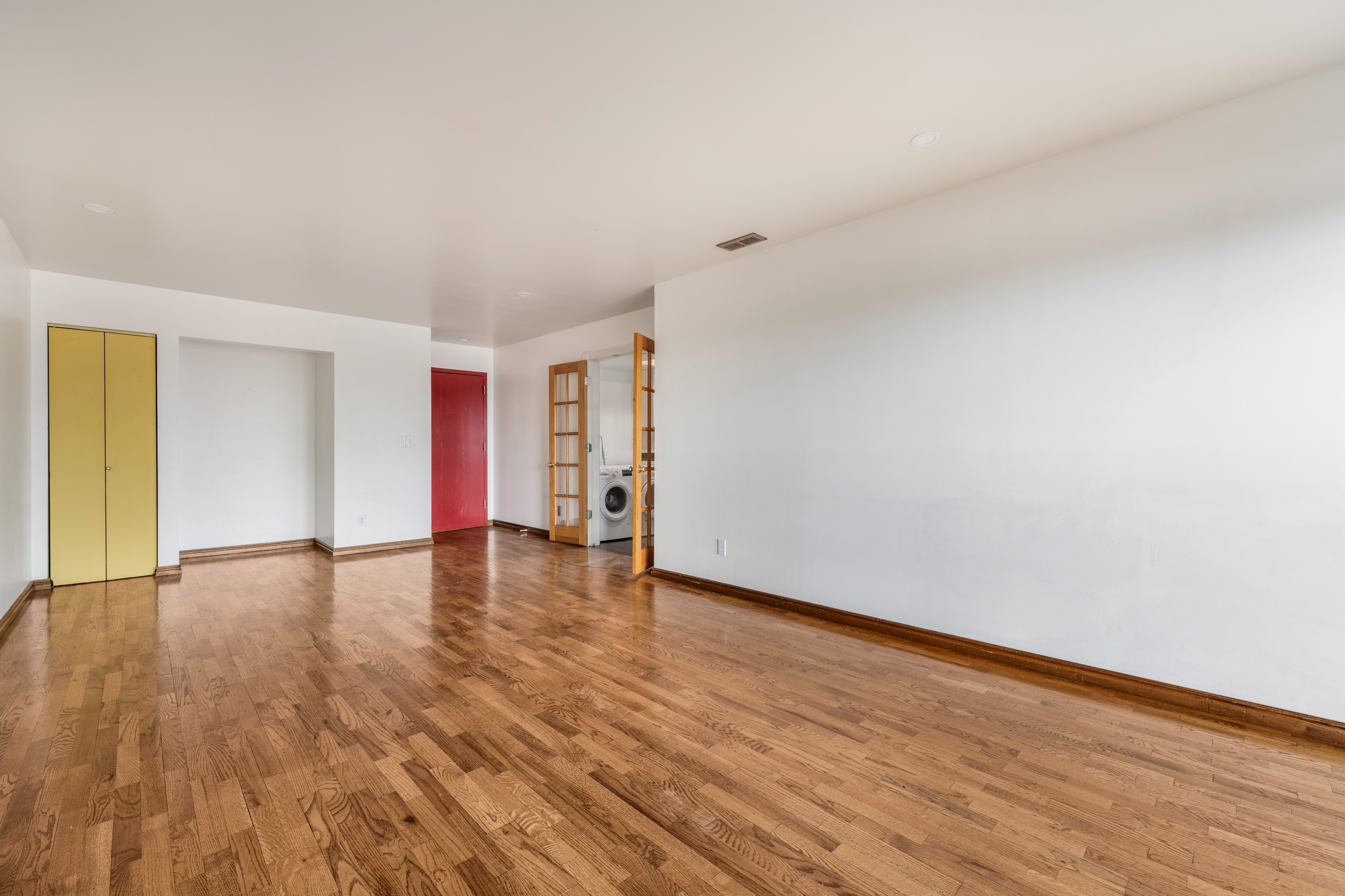 Expansive room featuring wood-finish flooring, white walls, and a recessed lighting fixture