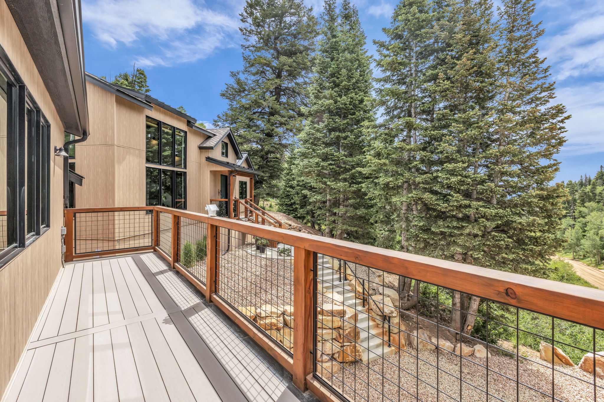 Outdoor deck featuring composite decking and a wood railing with black mesh infill