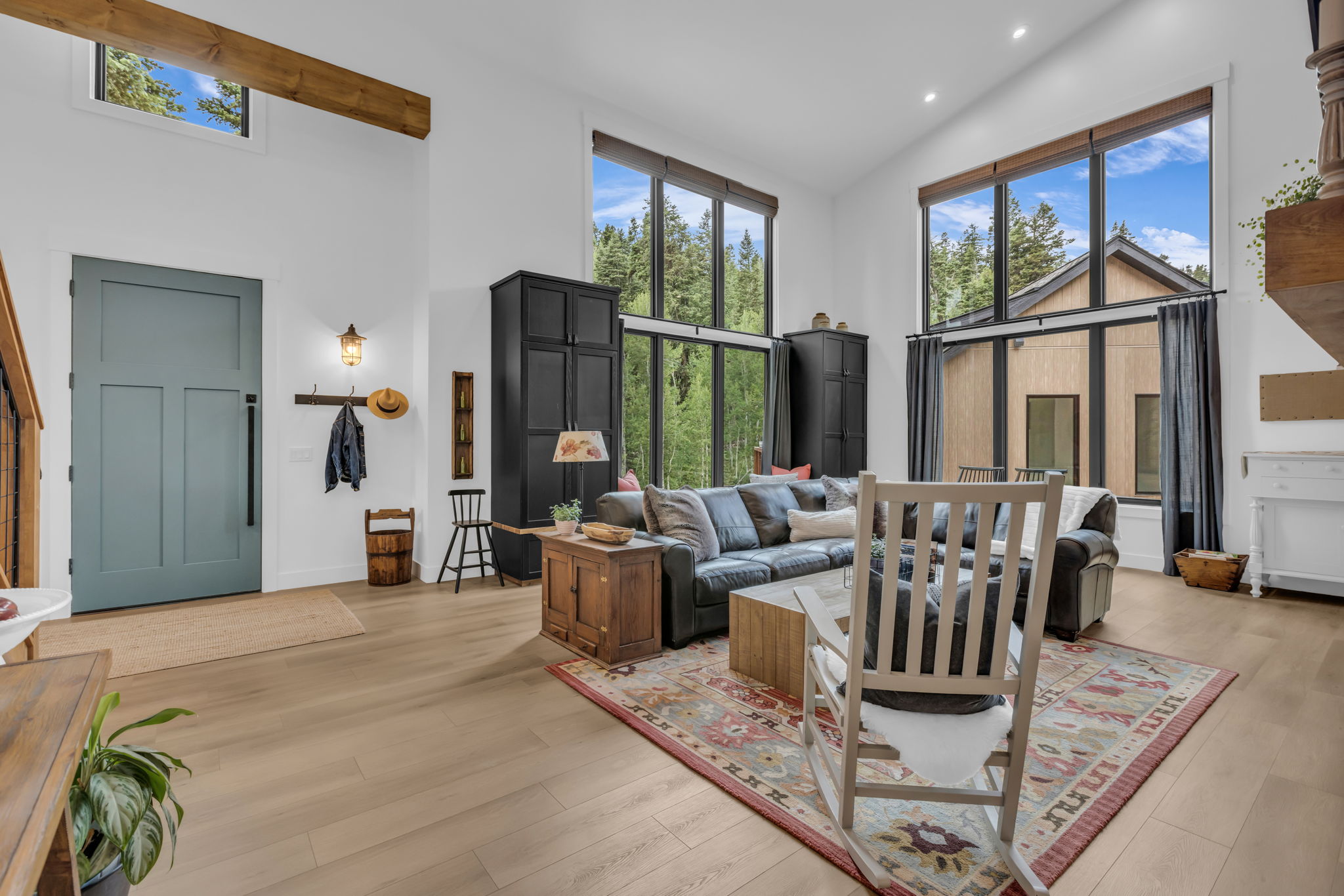 Open-concept living space featuring high ceilings, light wood-finish flooring, and expansive windows