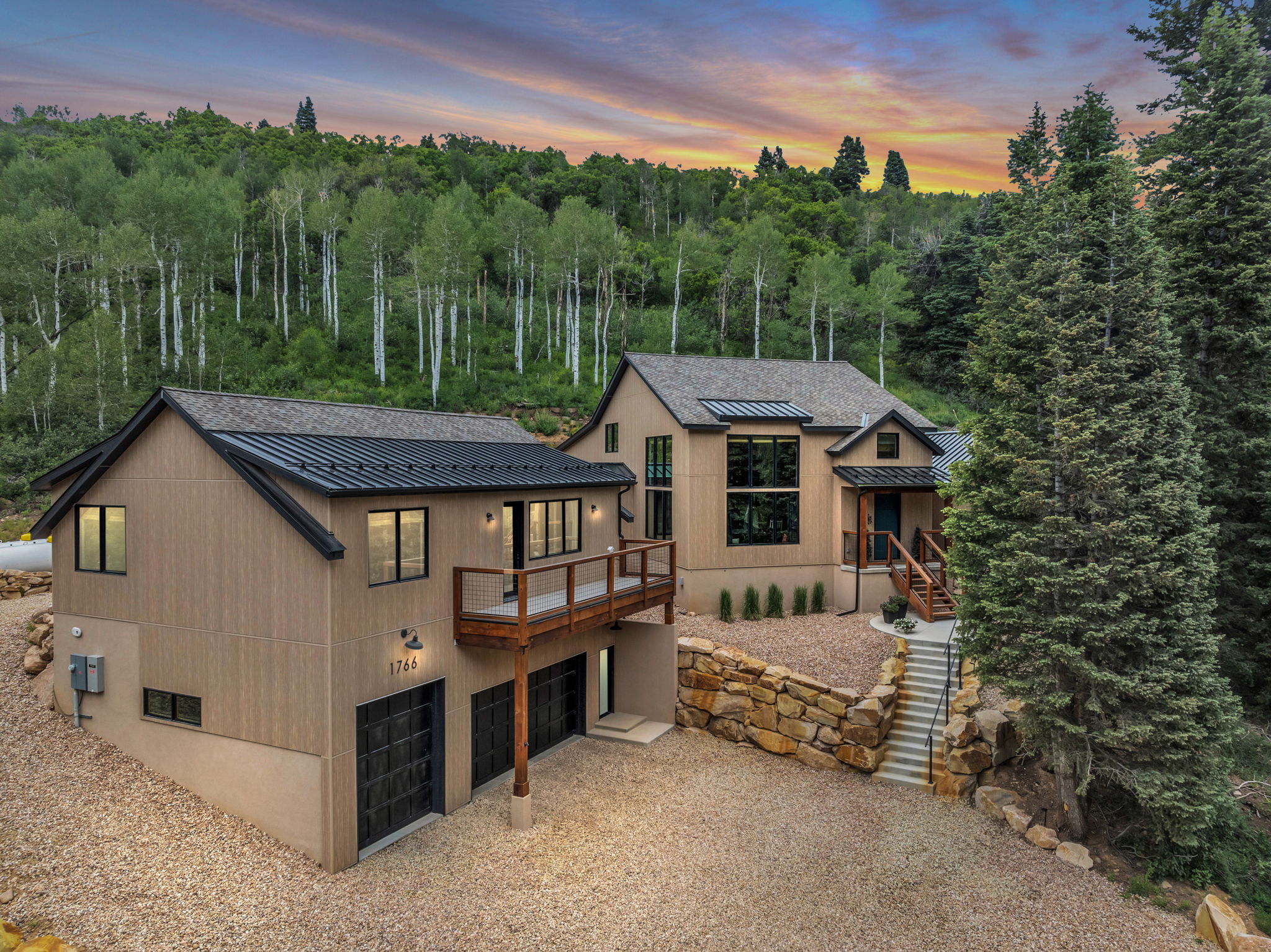Modern mountain-style dwelling featuring a light brown wood-look facade, dark metal roofing, and multiple levels of large windows