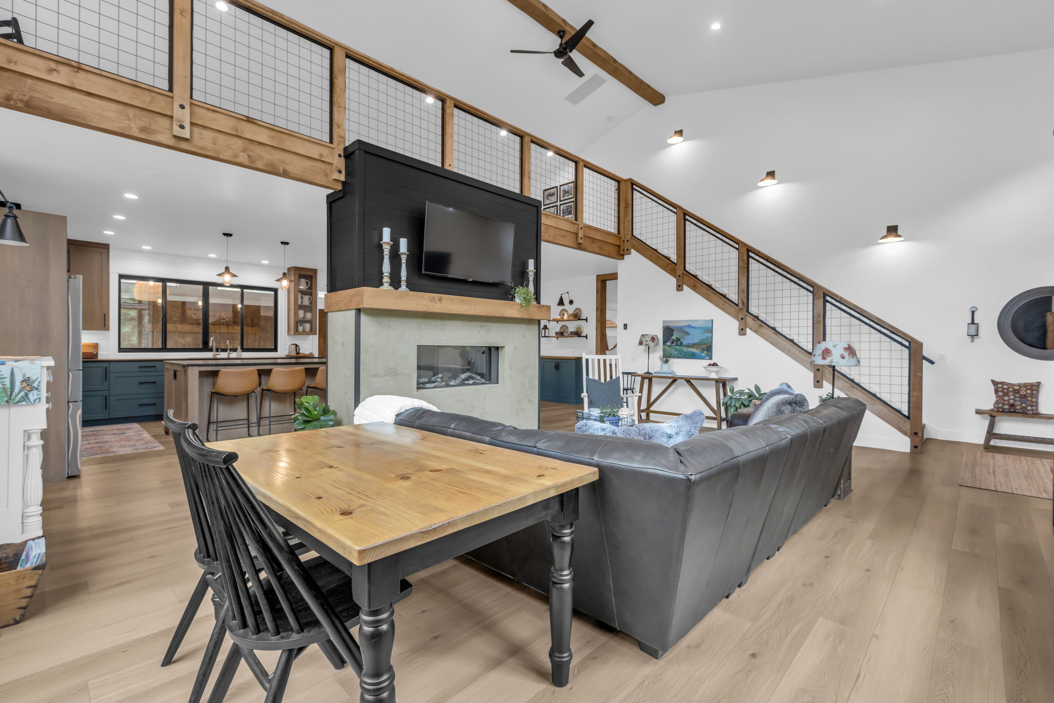 Open-concept living area with vaulted ceilings, light wood-finish flooring, and a modern fireplace