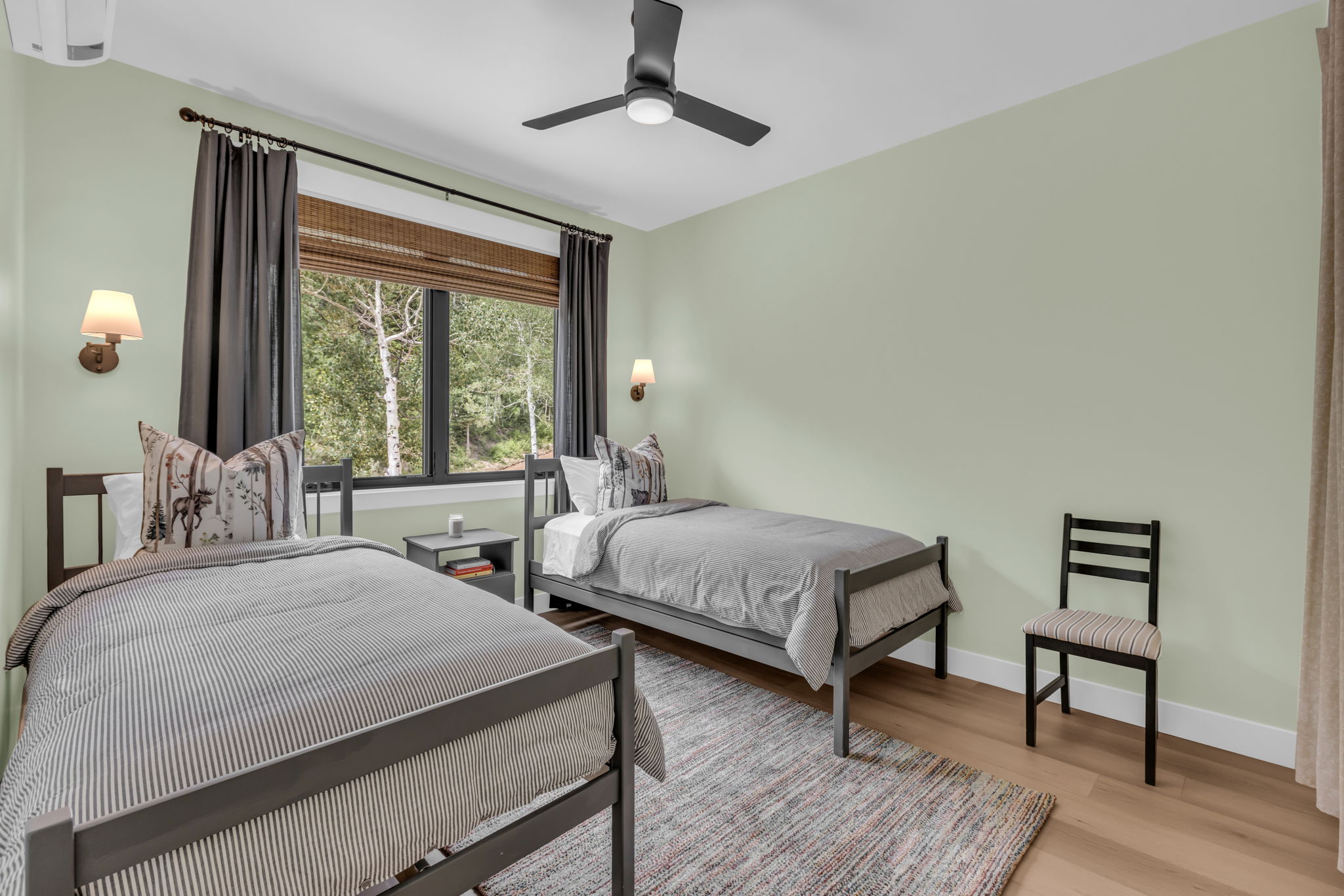Well-lit room featuring wood-finish flooring and a central ceiling fan