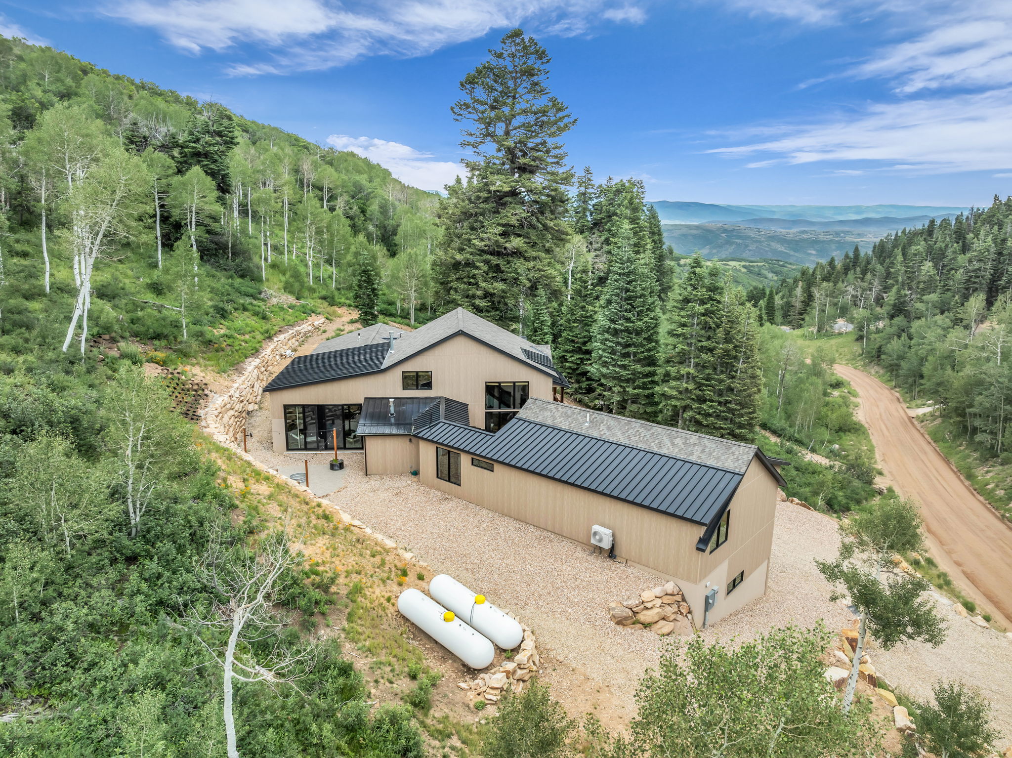 Modern mountain residence featuring a light-toned exterior siding and dark metal roofing