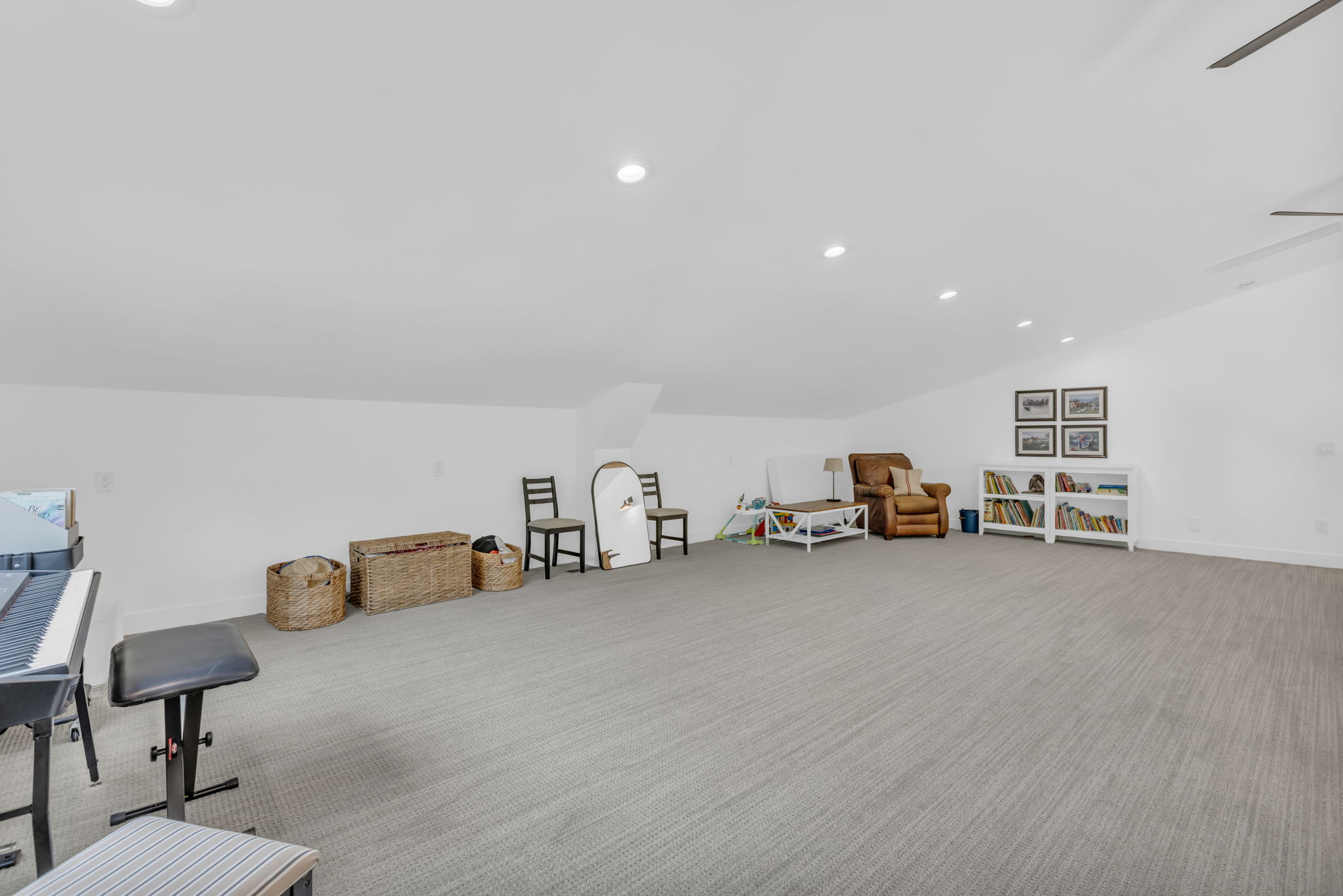 Spacious carpeted room featuring recessed lighting, a sloped ceiling, and a ceiling fan
