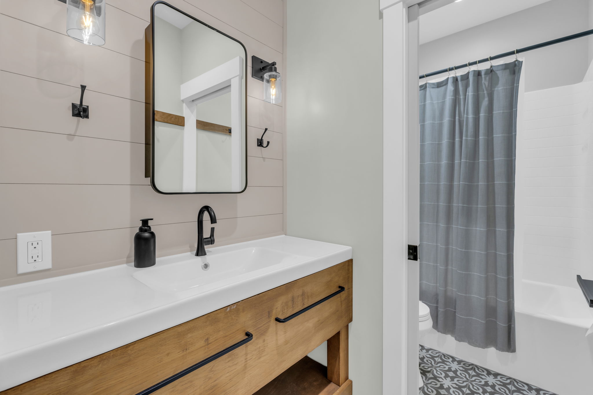 Bathroom featuring a rectangular sink set in a wood-finish vanity, matte black faucet, and a rectangular framed mirror