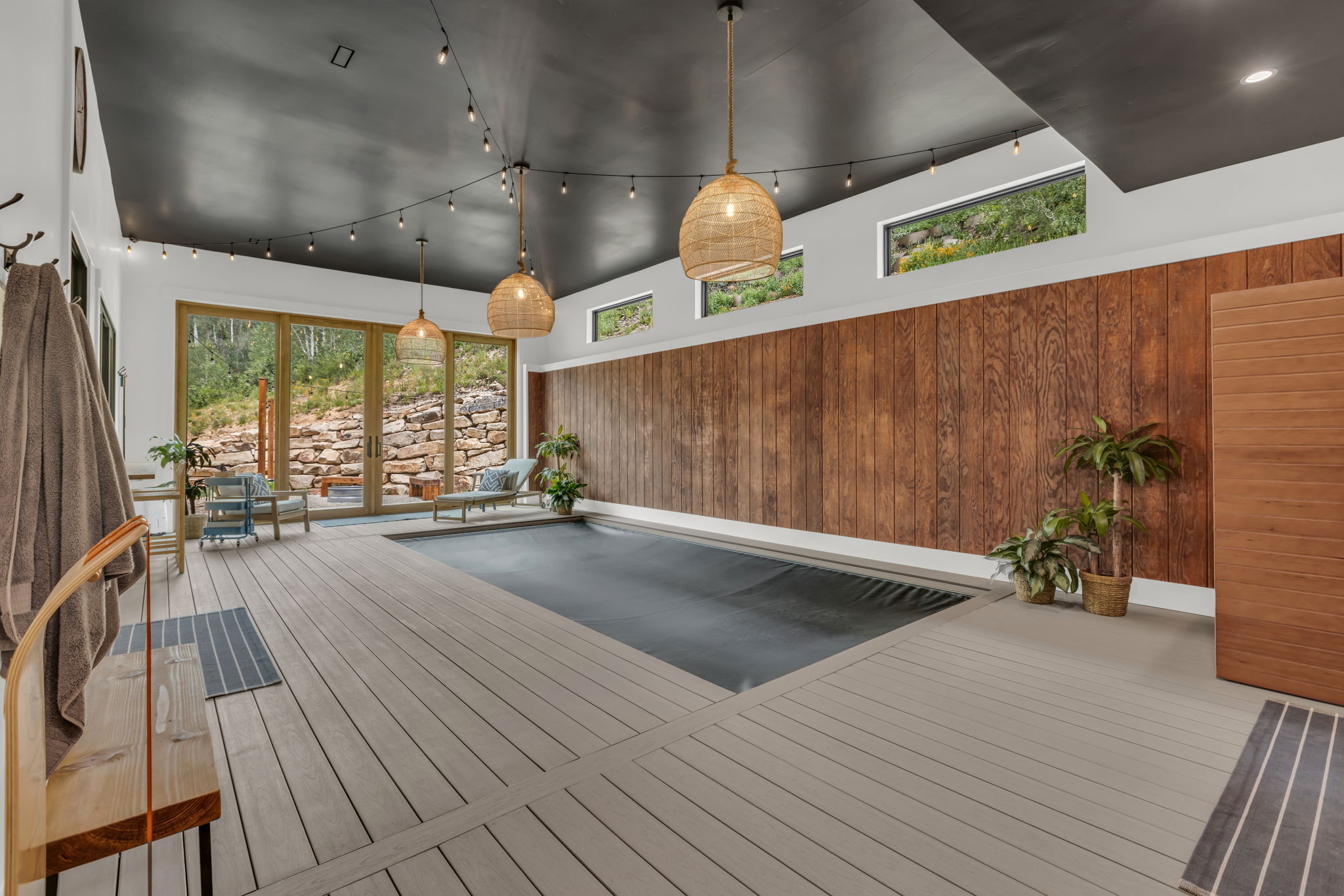 Indoor swimming pool area featuring wide plank deck flooring, a dark ceiling, and wood panel accent walls