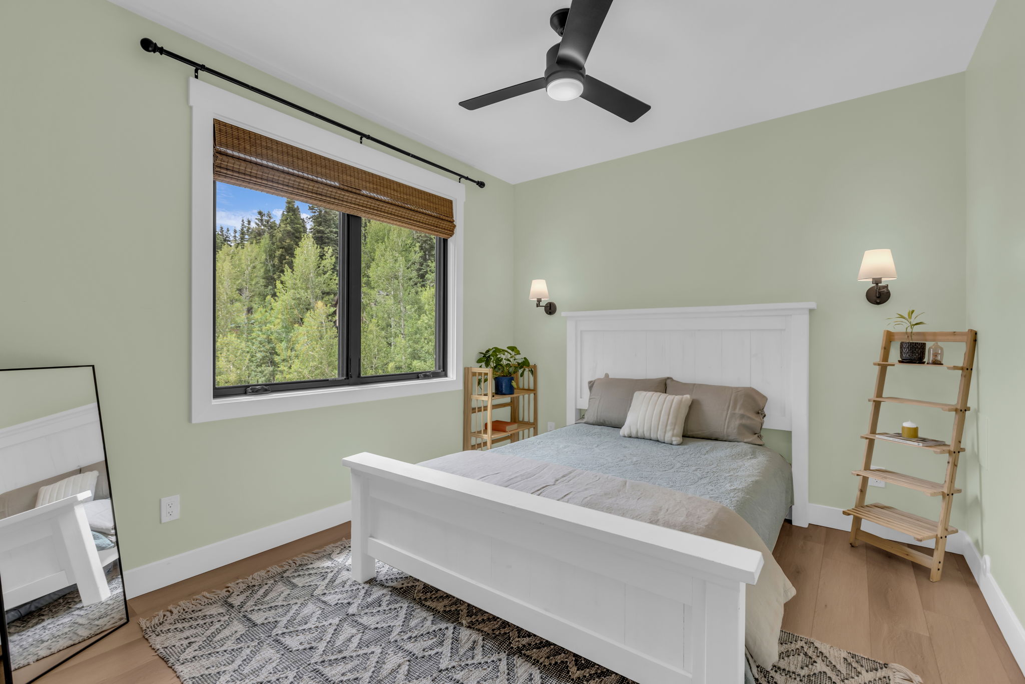Bedroom featuring a large picture window, wood-finish flooring, ceiling fan, and wall sconces