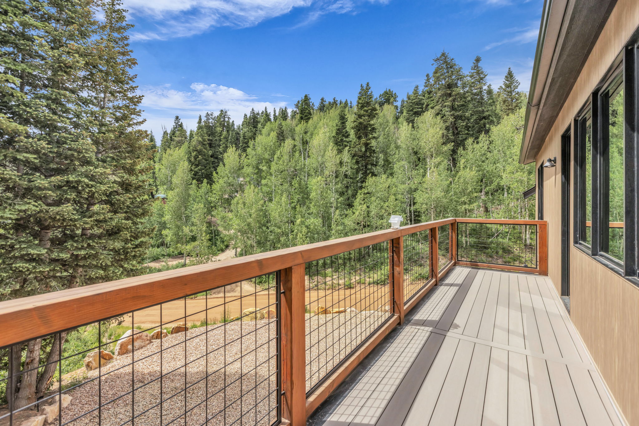 Spacious outdoor deck featuring composite decking, wood-toned railings with metal infill, and exterior wall sconces